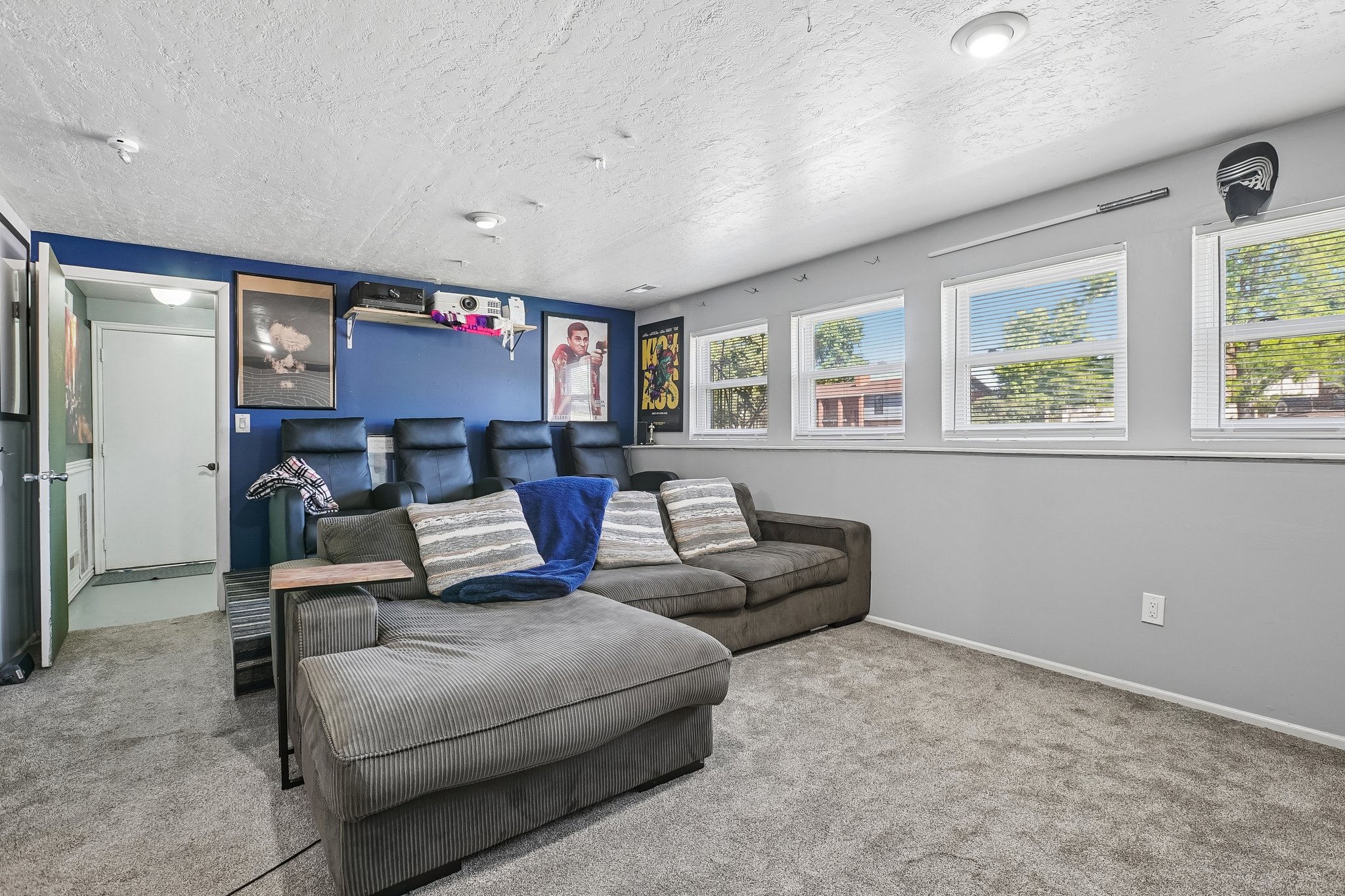 Carpeted room featuring a dedicated theater seating area, multiple windows with blinds, a contrasting accent wall, and recessed lighting