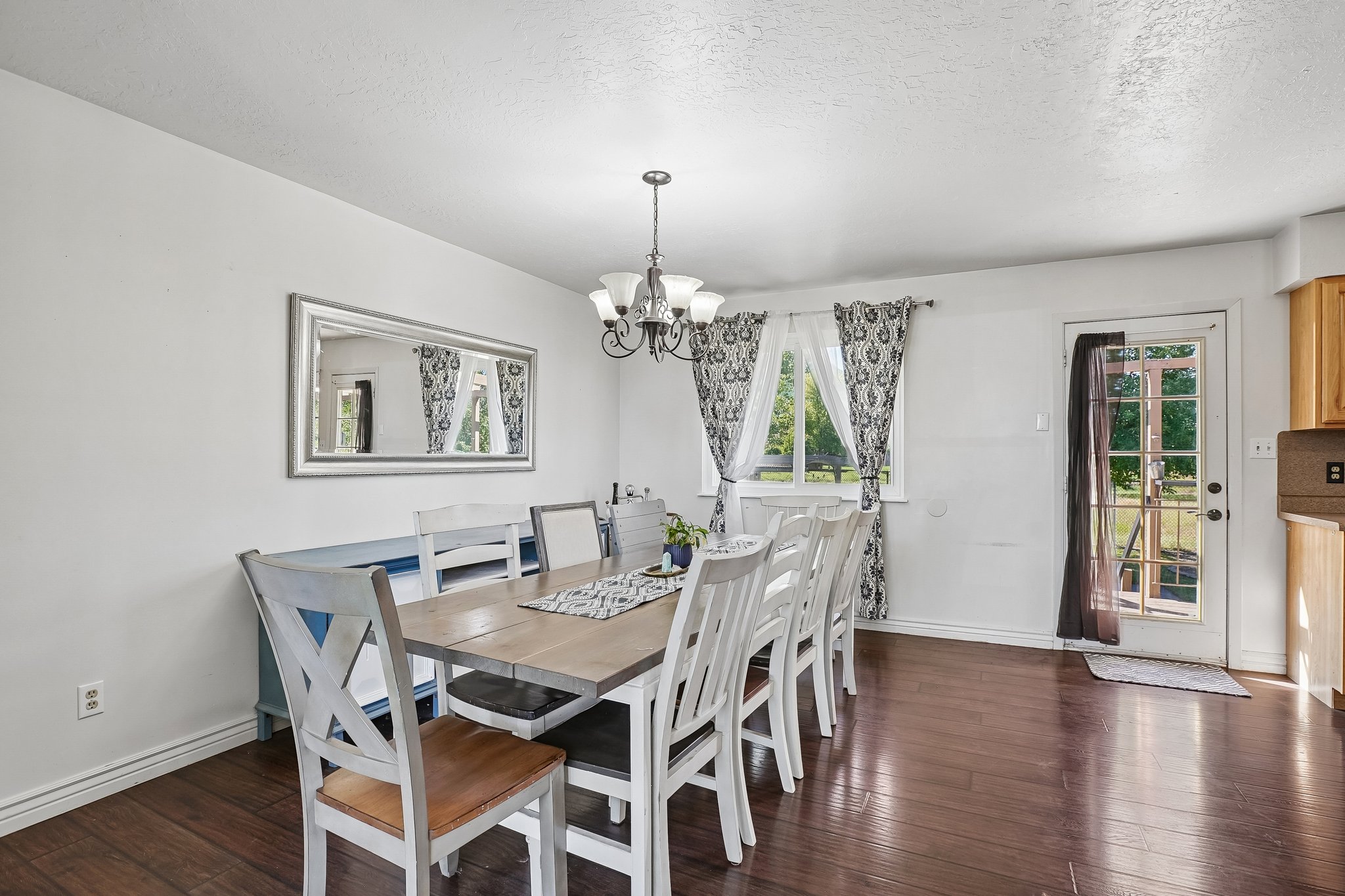 Dining area featuring rich wood-finish flooring, white walls, and a chandelier light fixture