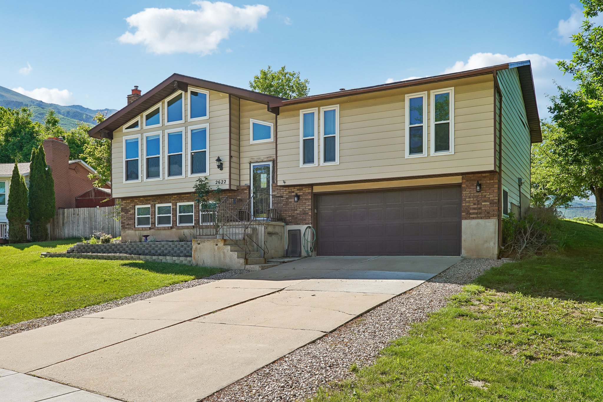 Split-level residence featuring a two-car garage, concrete driveway, and a combination of brick and siding exterior