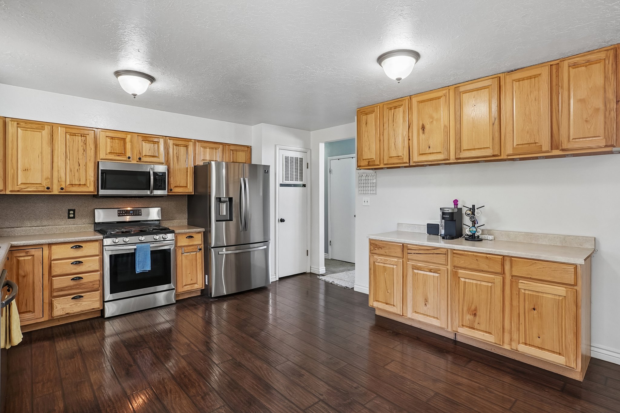 Kitchen featuring wood-finish flooring, natural wood cabinetry, stainless steel appliances, and light-toned countertops