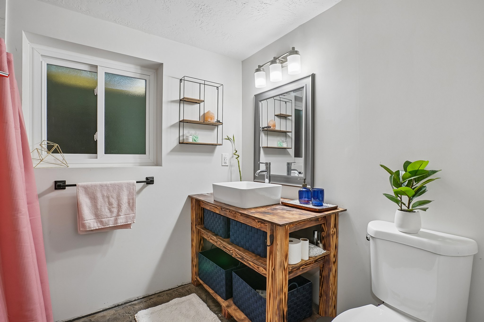 Bathroom featuring a wood-finish vanity with an integrated vessel sink and a wall-mounted mirror