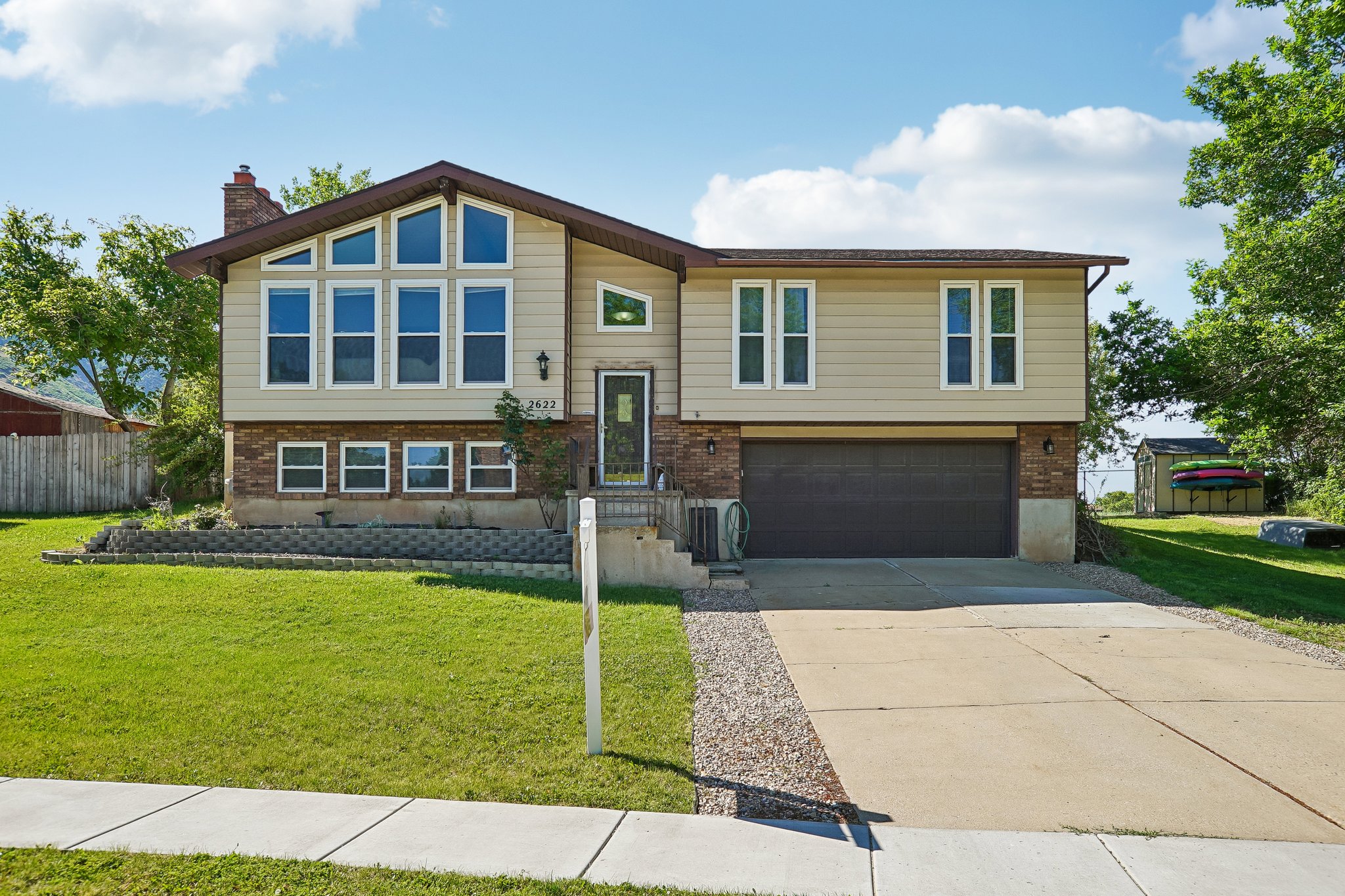 Split-level residence featuring a prominent multi-pane window array, tan siding, and a brick facade accent