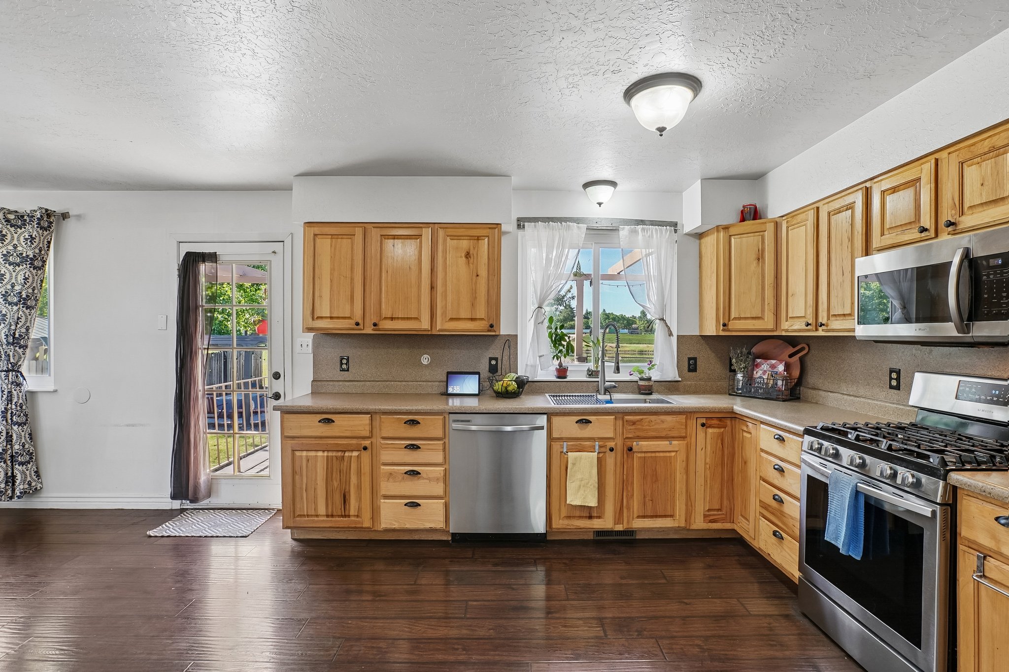 Kitchen featuring wood-finish flooring, ample wood cabinetry, a stainless steel gas range, a stainless steel microwave, and a stainless steel dishwasher