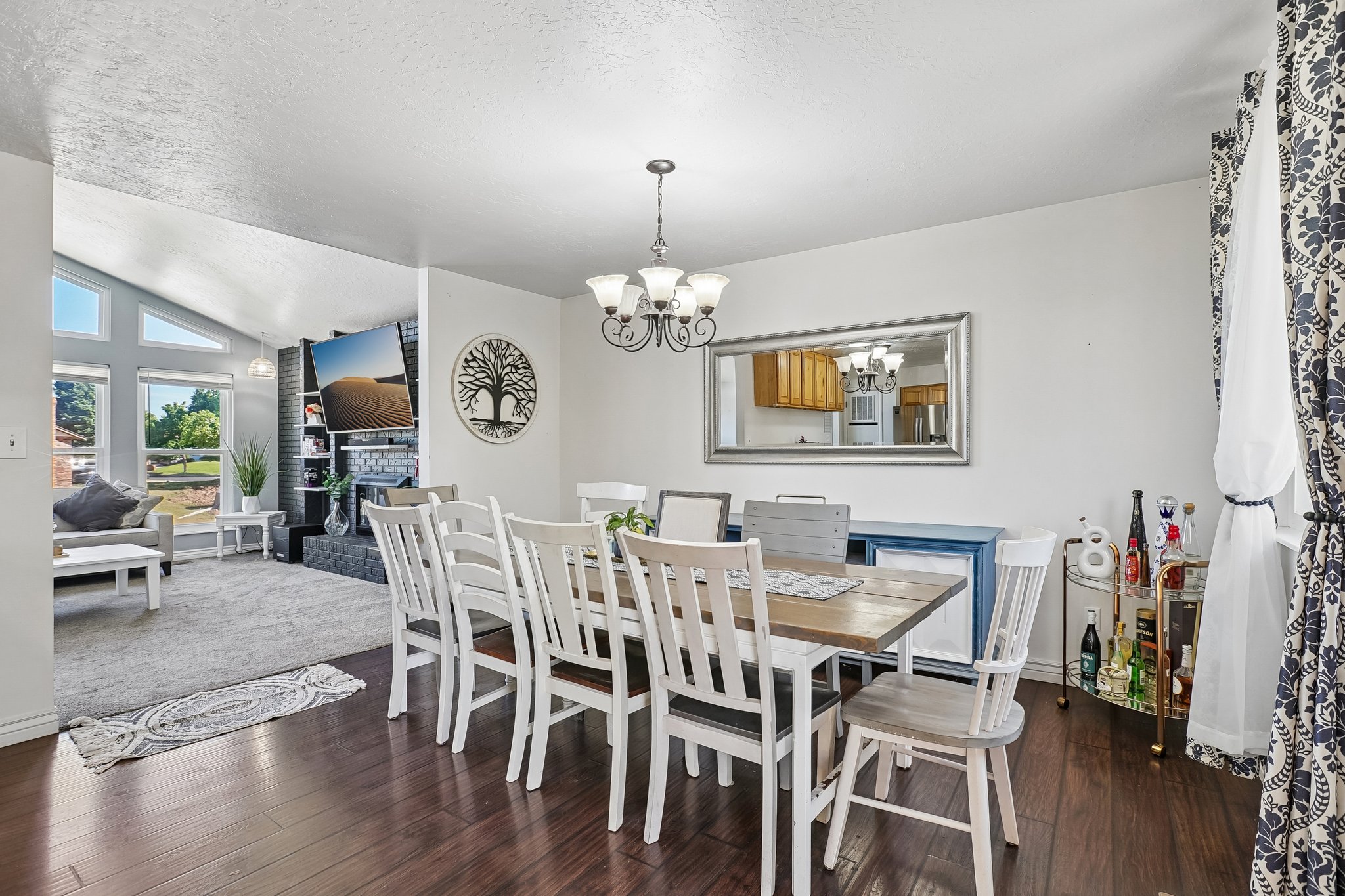 Wood-finish flooring anchors this dining area, featuring a decorative chandelier and a framed mirror