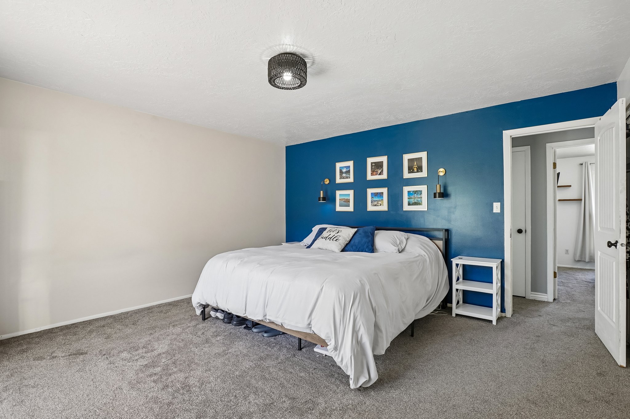 Bedroom featuring plush carpeting, a dramatic accent wall, a ceiling-mounted light fixture, and a white paneled door