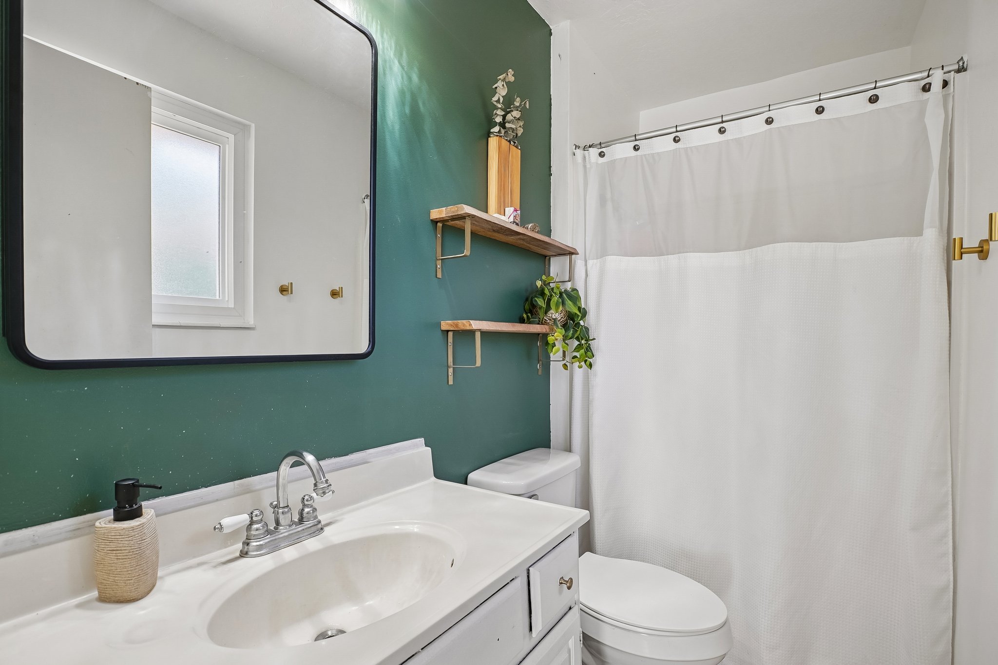 Bathroom featuring a white vanity with integrated sink, chrome faucet, and a large black-framed mirror