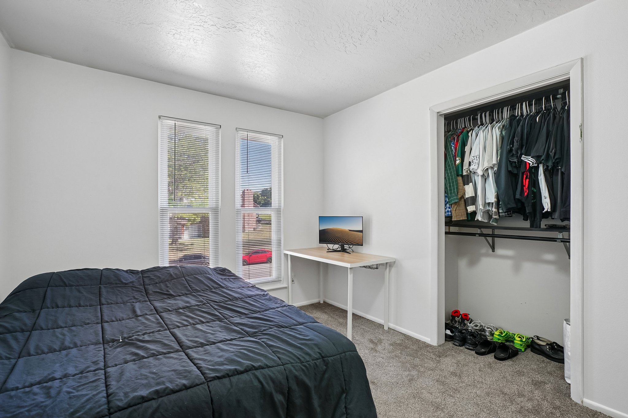 Bedroom featuring two windows with blinds, light gray wall paint, and gray carpet flooring