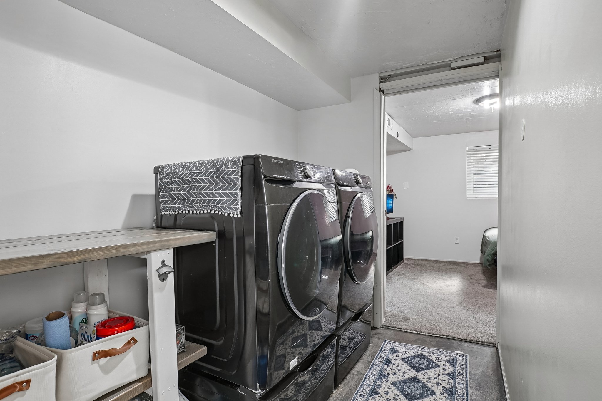 Dedicated laundry area featuring a wood-finish countertop and crisp white walls