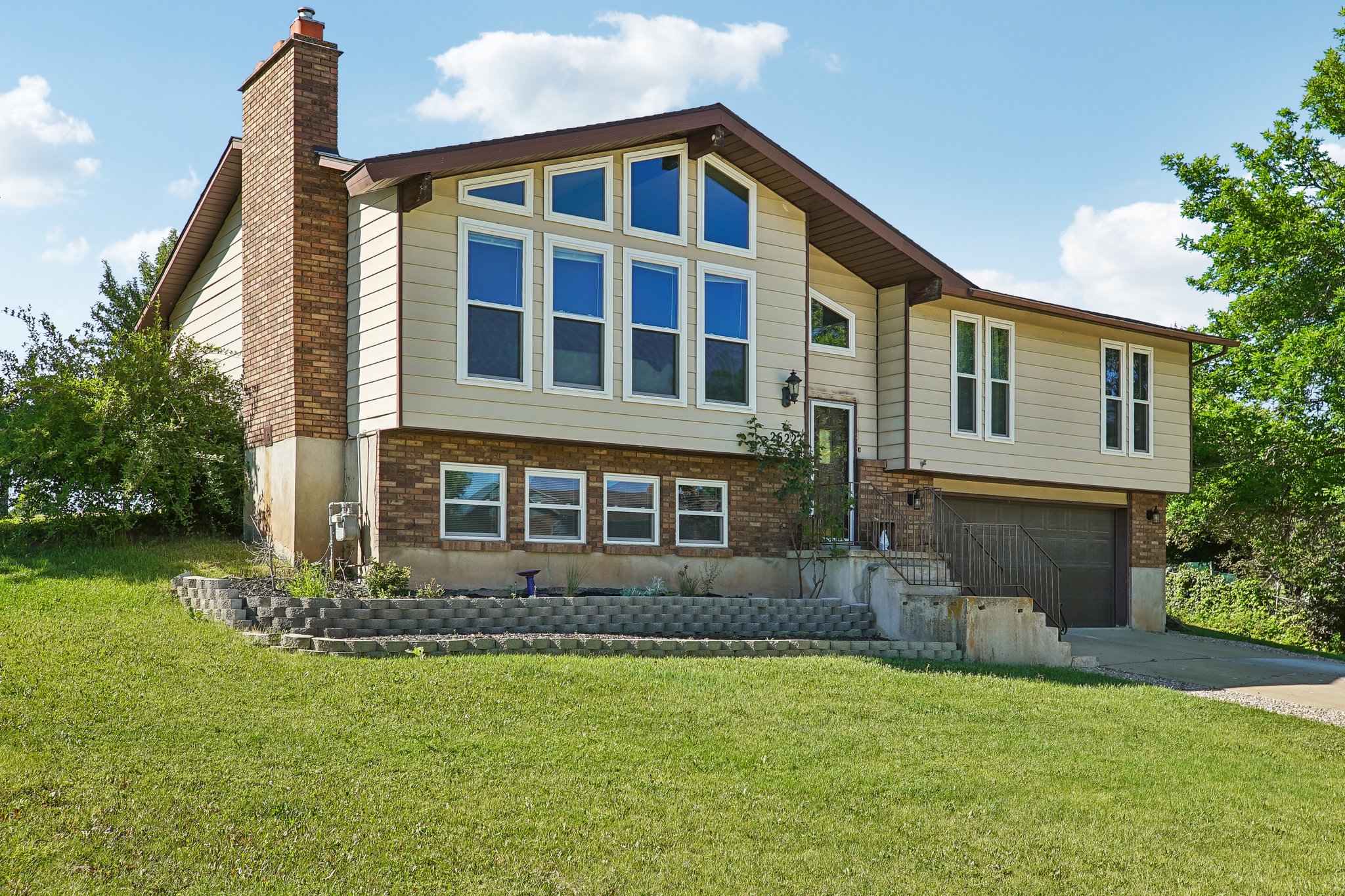 Split-level residence featuring a brick chimney, stacked window configuration, and a two-tone exterior finish