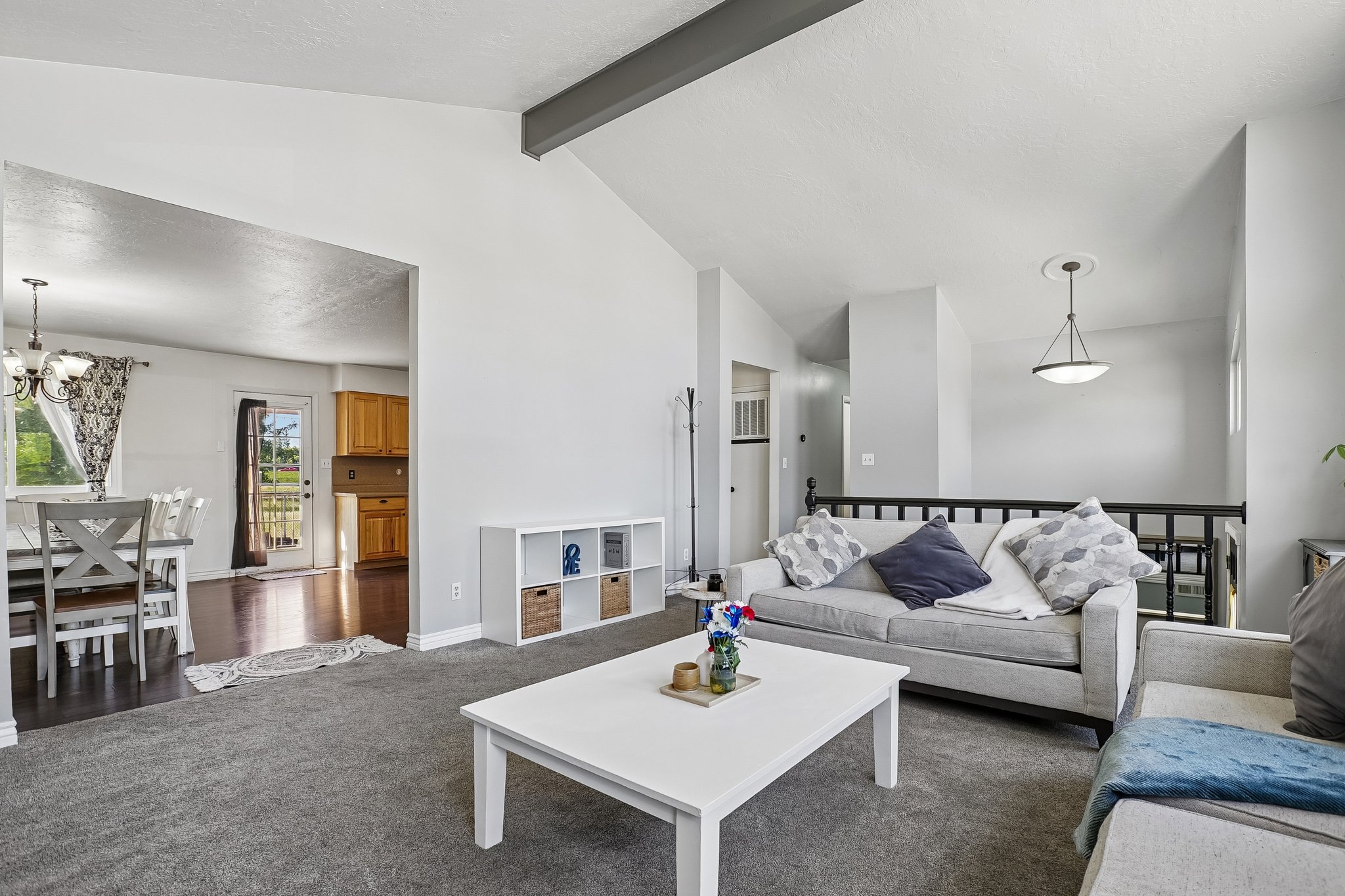 Vaulted ceilings featuring an exposed beam, grey carpeting, and an open concept layout
