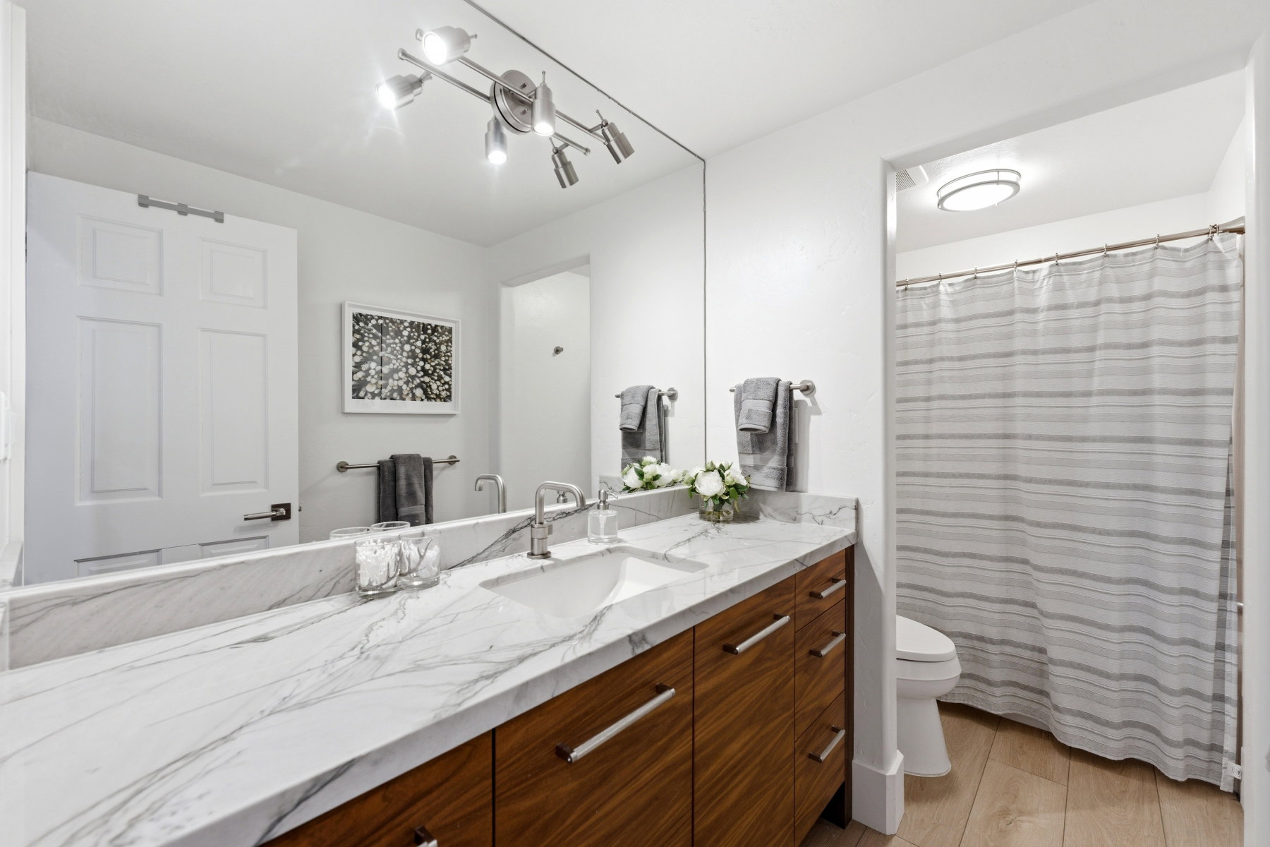 Bathroom vanity featuring a single basin, brushed nickel faucet, and a large wall-mounted mirror