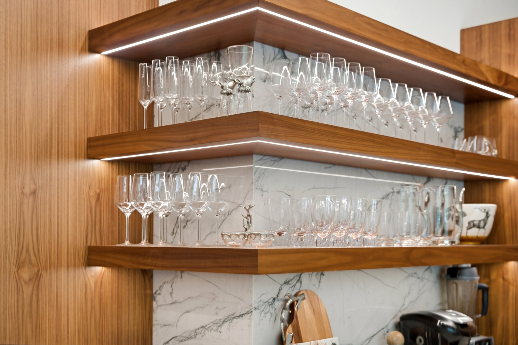 Built-in open shelving with integrated lighting, wood-finish construction, and a stone-patterned backsplash