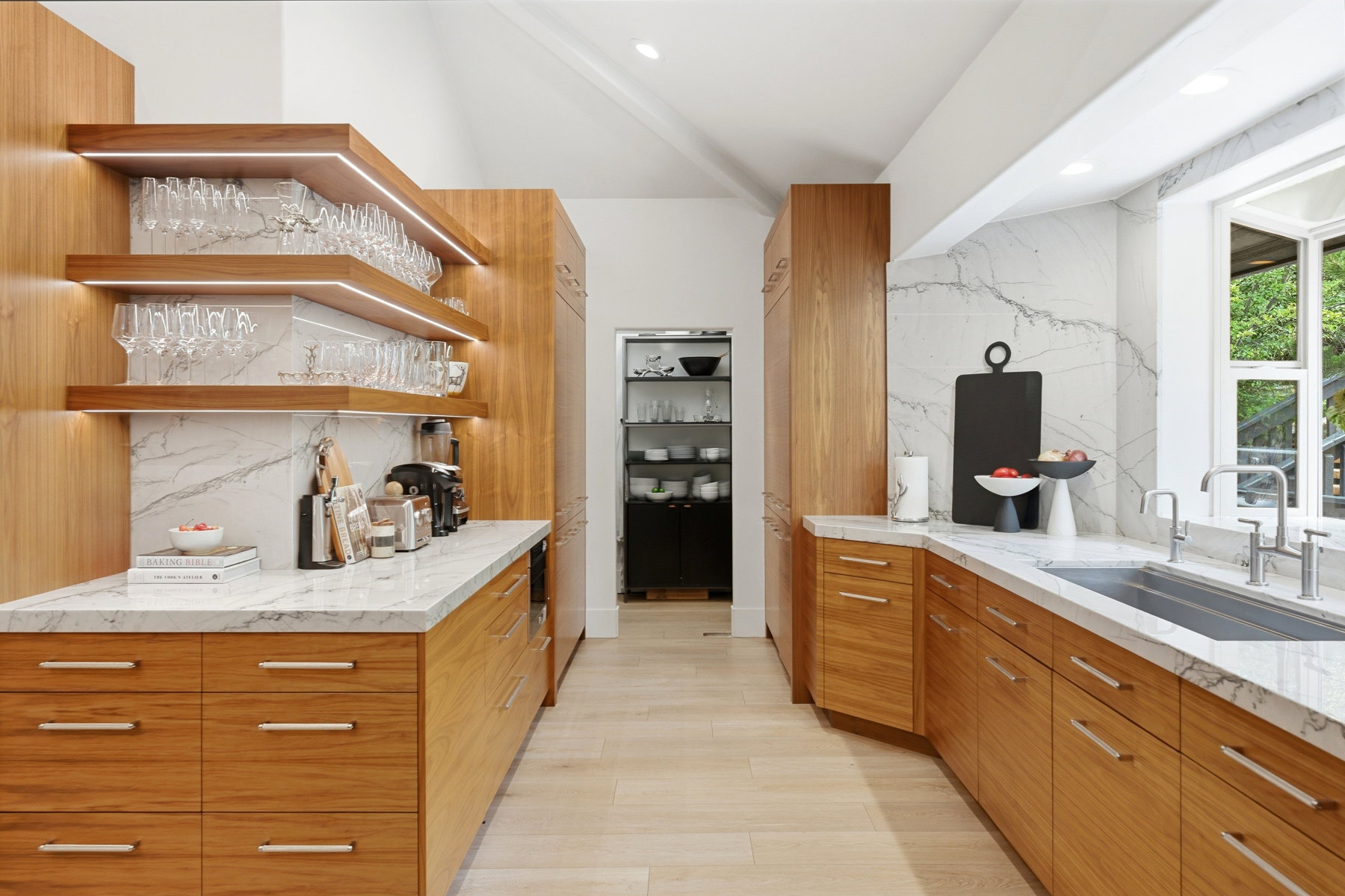 Kitchen featuring light wood-finish cabinetry, white stone countertops, and a full-height stone slab backsplash