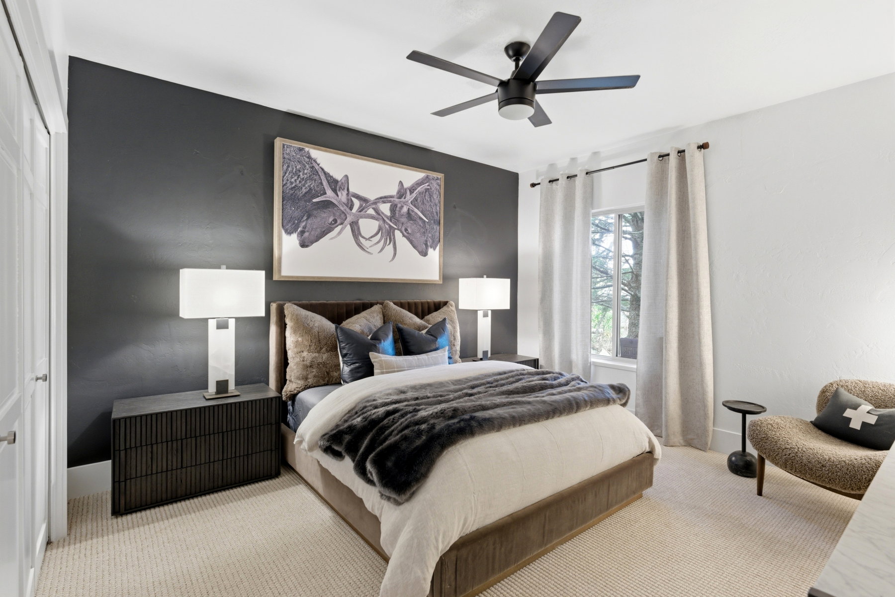 Bedroom featuring a dark accent wall, white window casement, and a ceiling fan