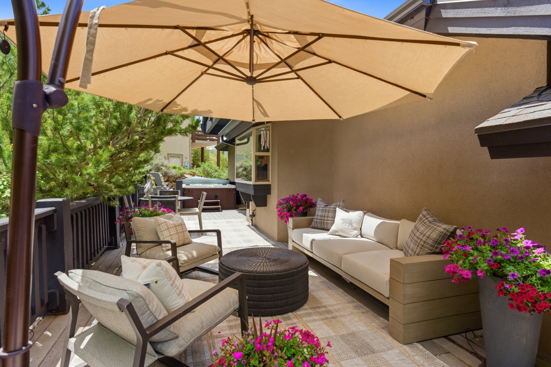 Expansive outdoor deck featuring wood-finish flooring, a built-in hot tub, and a tan patio umbrella
