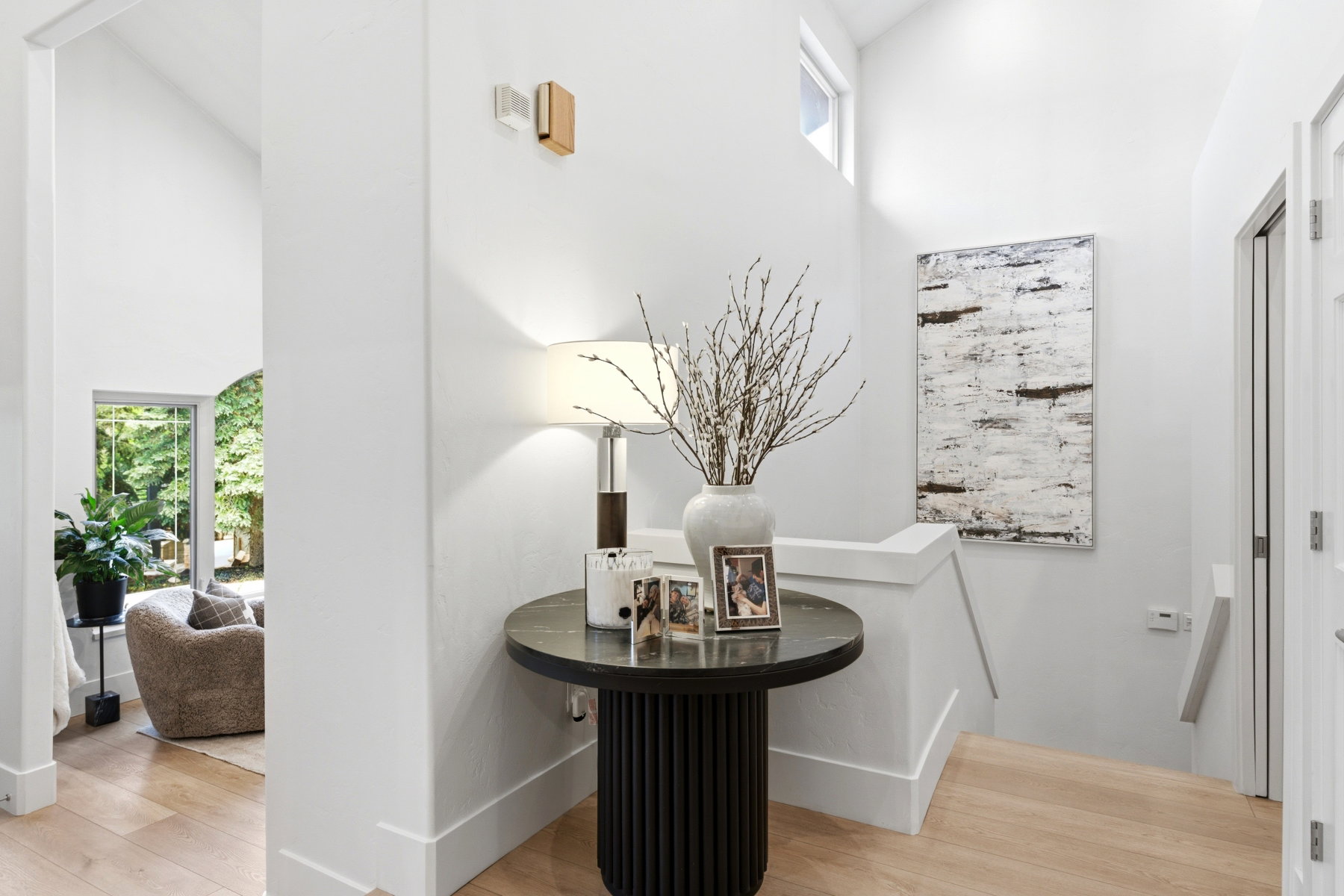 Bright entryway featuring light wood-finish flooring, white walls, and a staircase with a white railing
