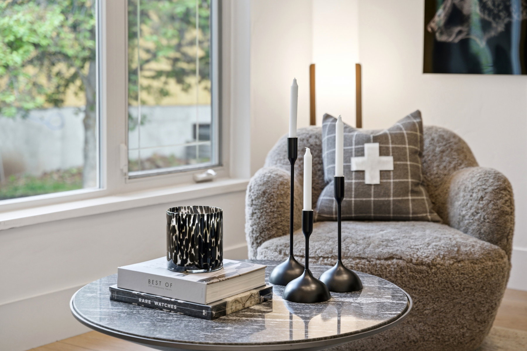 Double-pane window with white trim, light wood-finish flooring, and a round accent table featuring a dark stone-look top