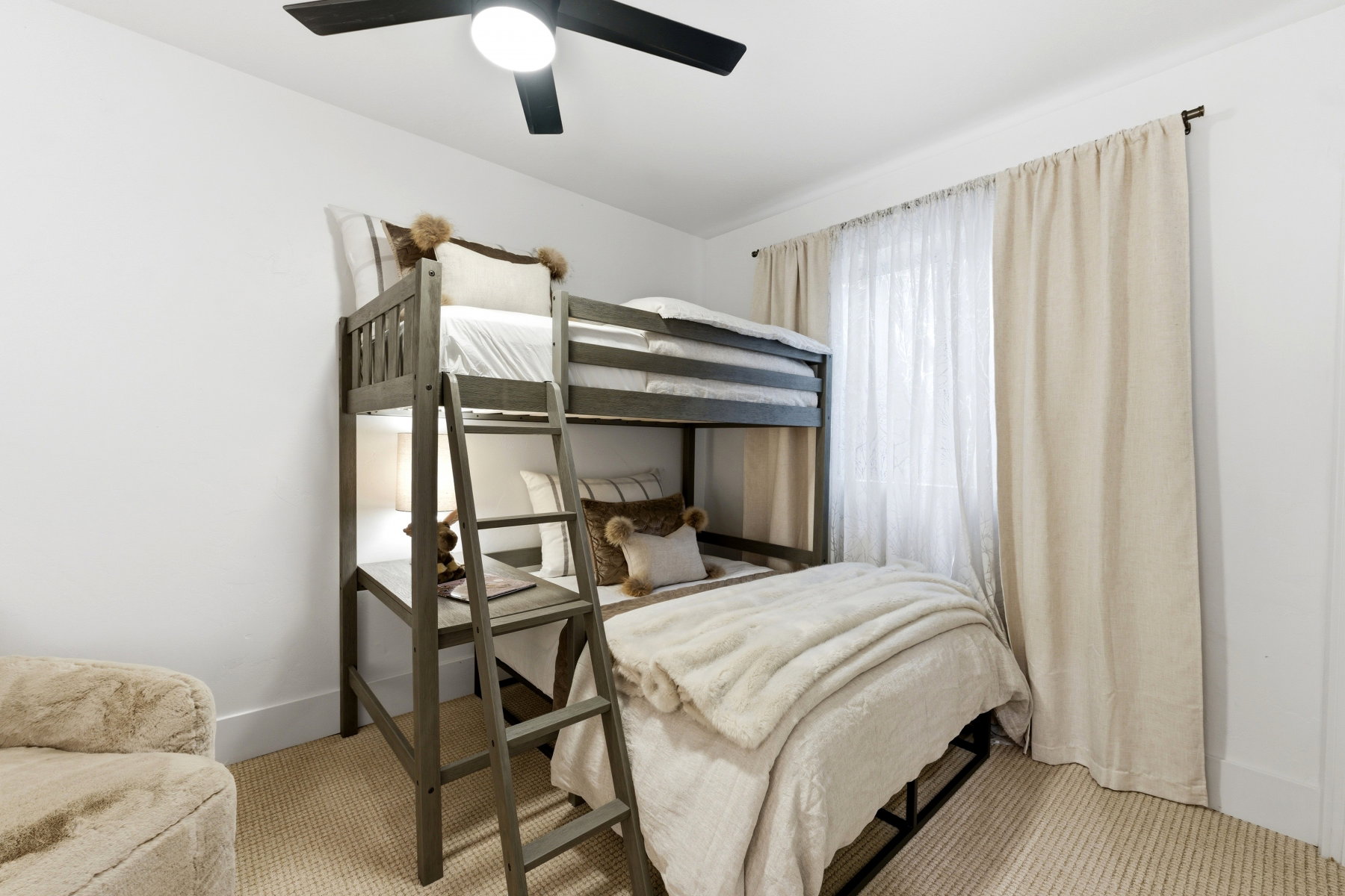 Bedroom featuring a built-in bunk bed, ceiling fan with integrated lighting, and a window with sheer and blackout drapery