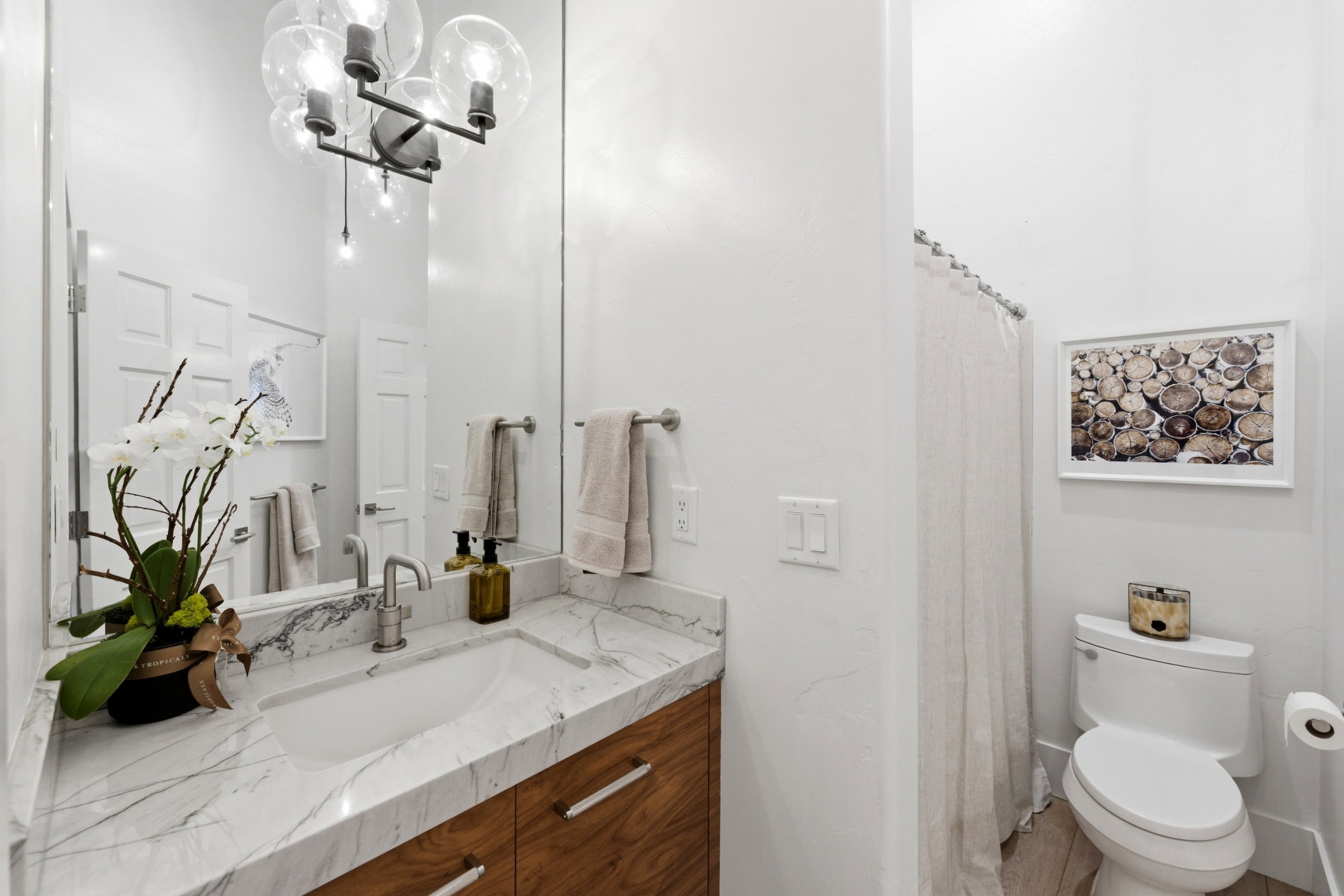 Bathroom with a wood-finish vanity featuring metal pull handles, a white countertop with grey veining, and an integrated rectangular sink
