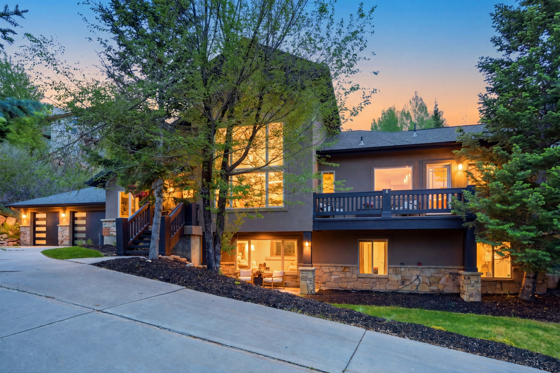 Contemporary residence featuring a multi-story facade with expansive windows, a private balcony, and a two-car garage with modern doors