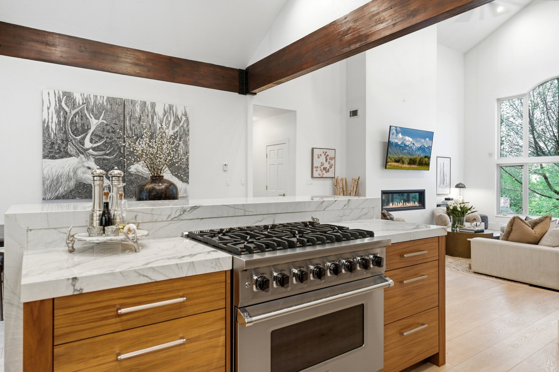 Gourmet kitchen with a stainless steel range and oven, natural wood-finish cabinetry, and white veined countertops
