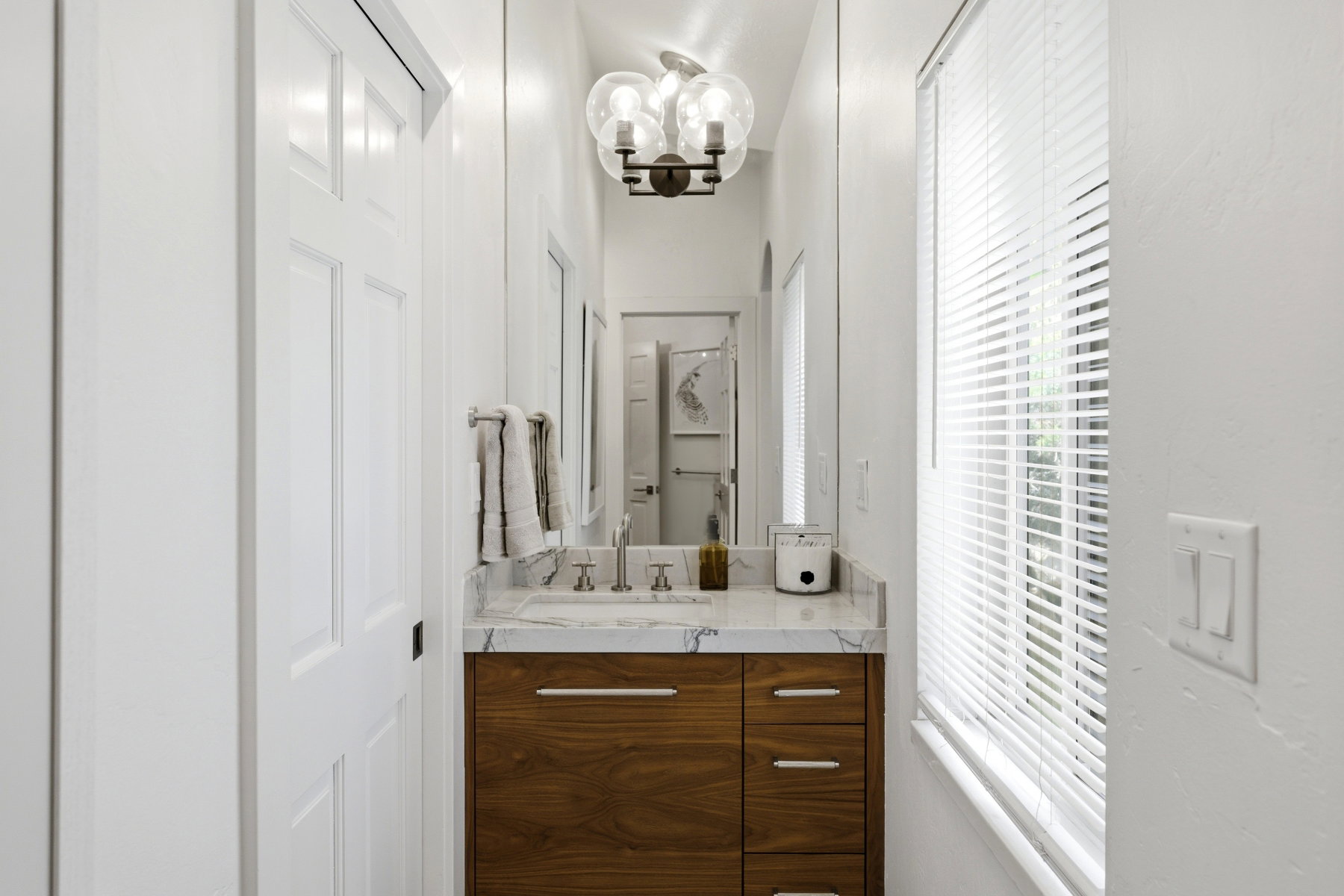Bathroom featuring a wood-finish vanity with a light-toned countertop, under-mount sink, and modern faucet