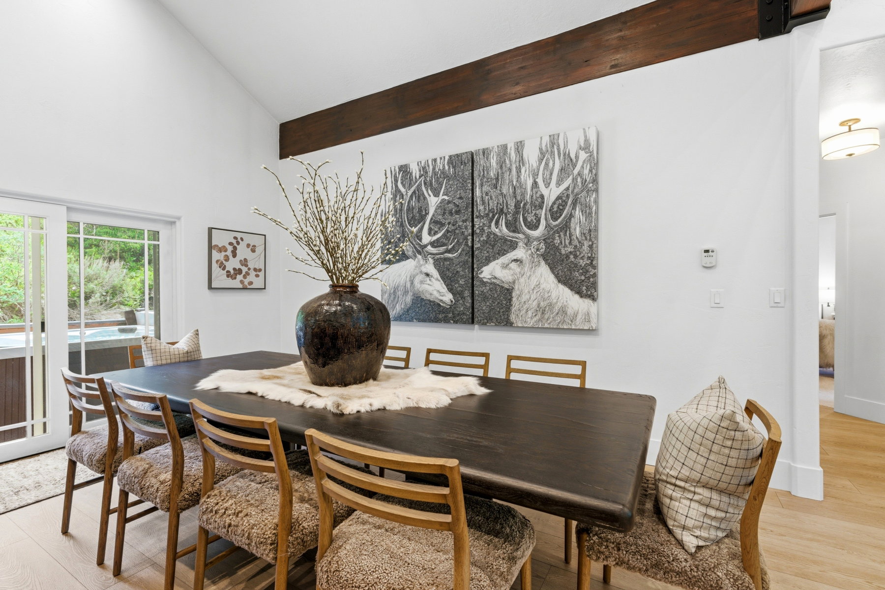 Dining area featuring a dark wood-finish table with upholstered seating, exposed ceiling beam, and light wood-finish flooring