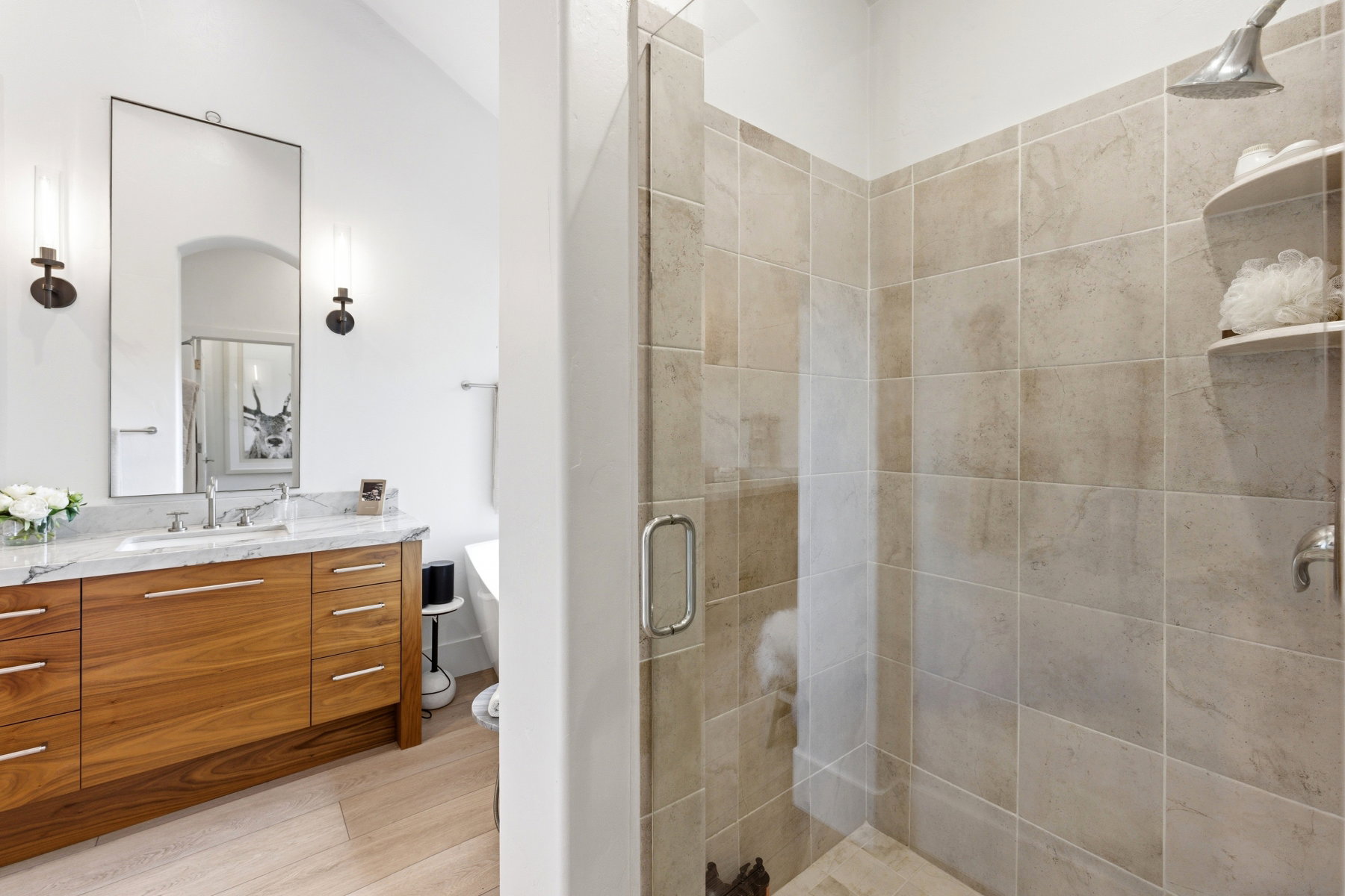 Glass-enclosed shower with ceramic tile surround and a built-in corner shelf