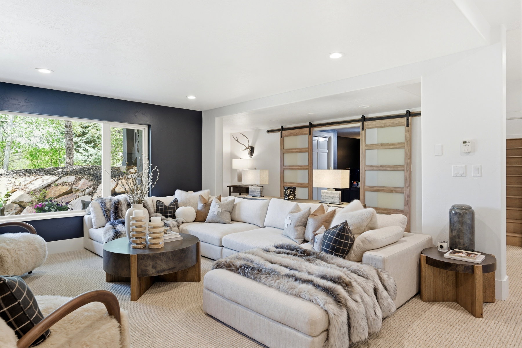 Spacious living area featuring a large picture window, recessed lighting, and barn doors with frosted glass panels