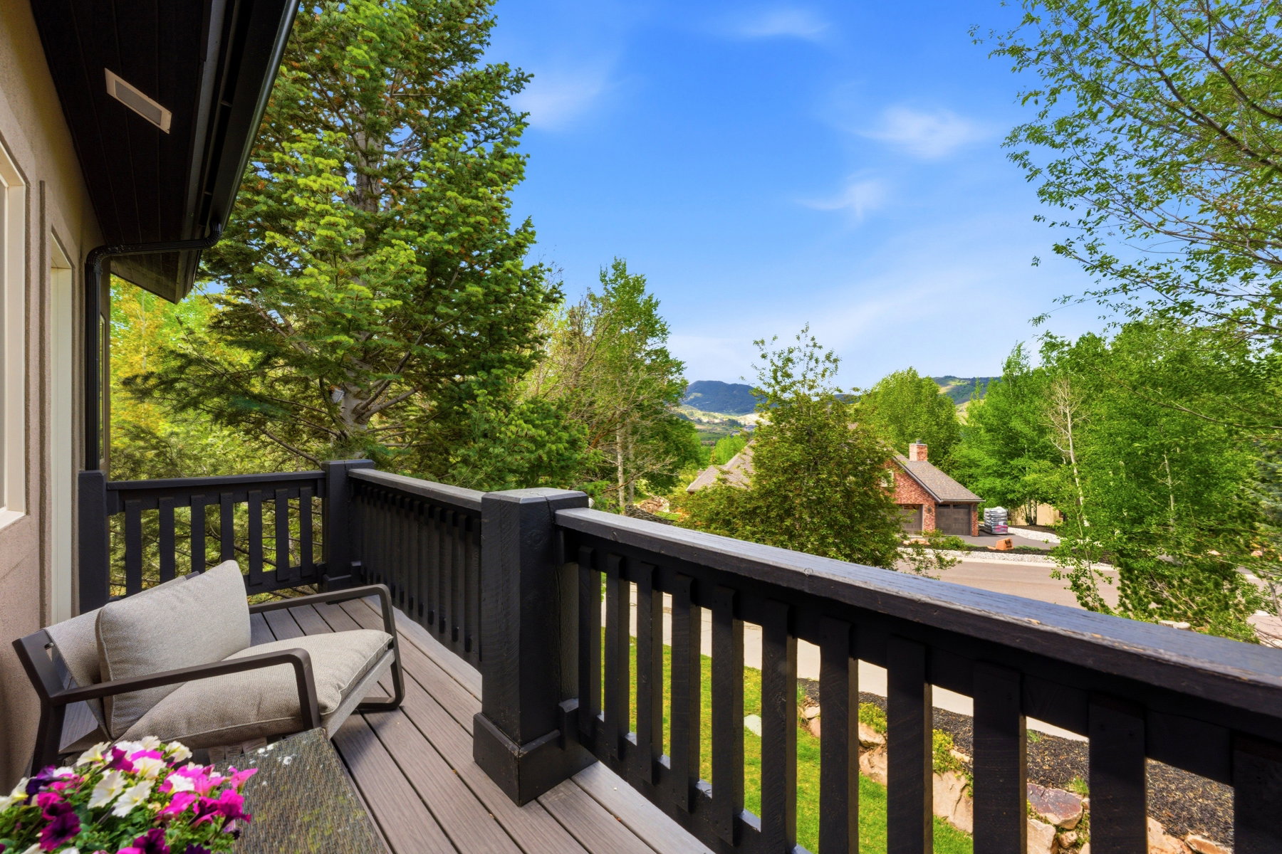 Outdoor balcony featuring composite decking, dark wood railings, and expansive tree-lined scenery