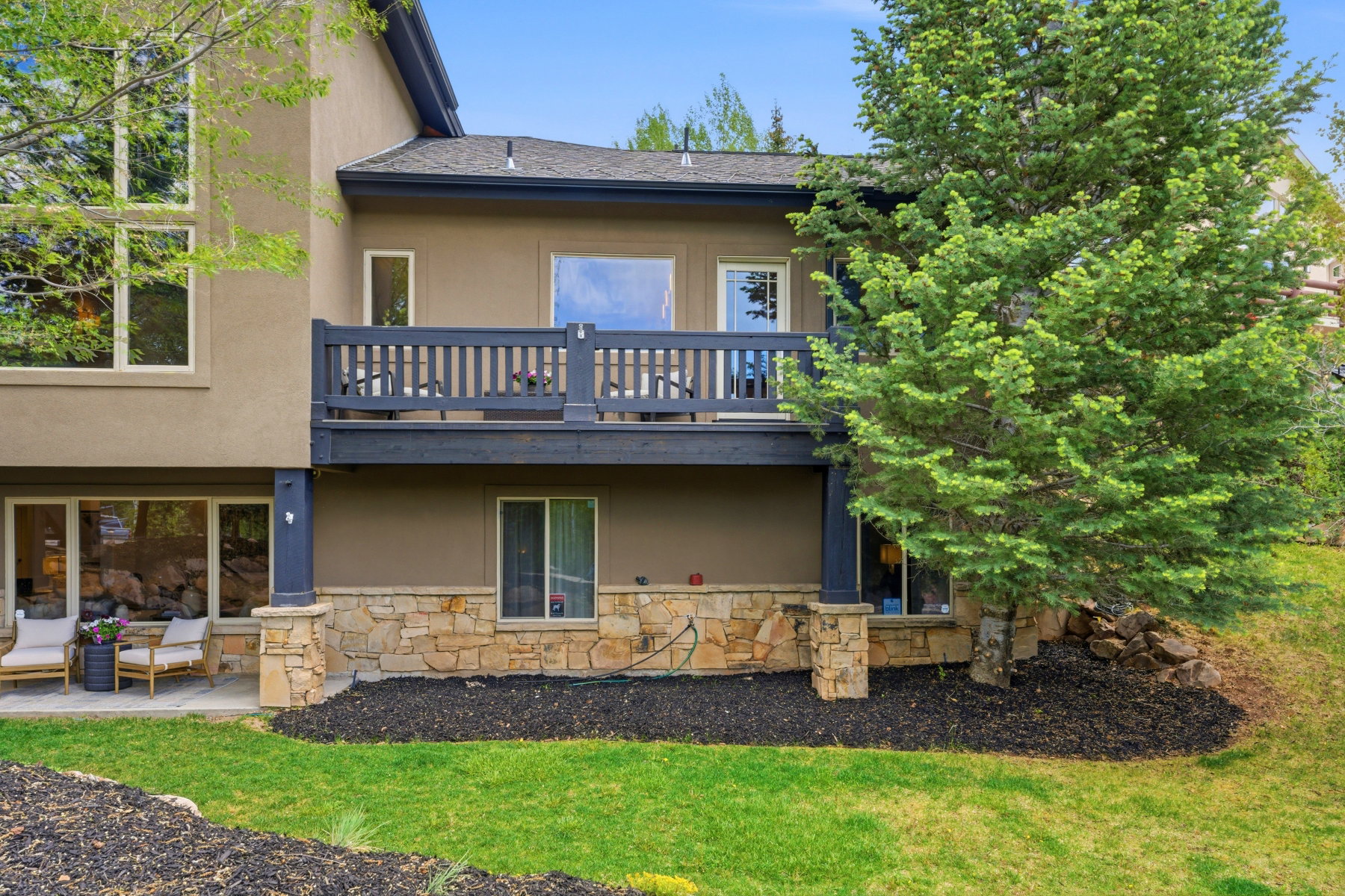 Multi-level rear exterior featuring stucco siding and stone accents