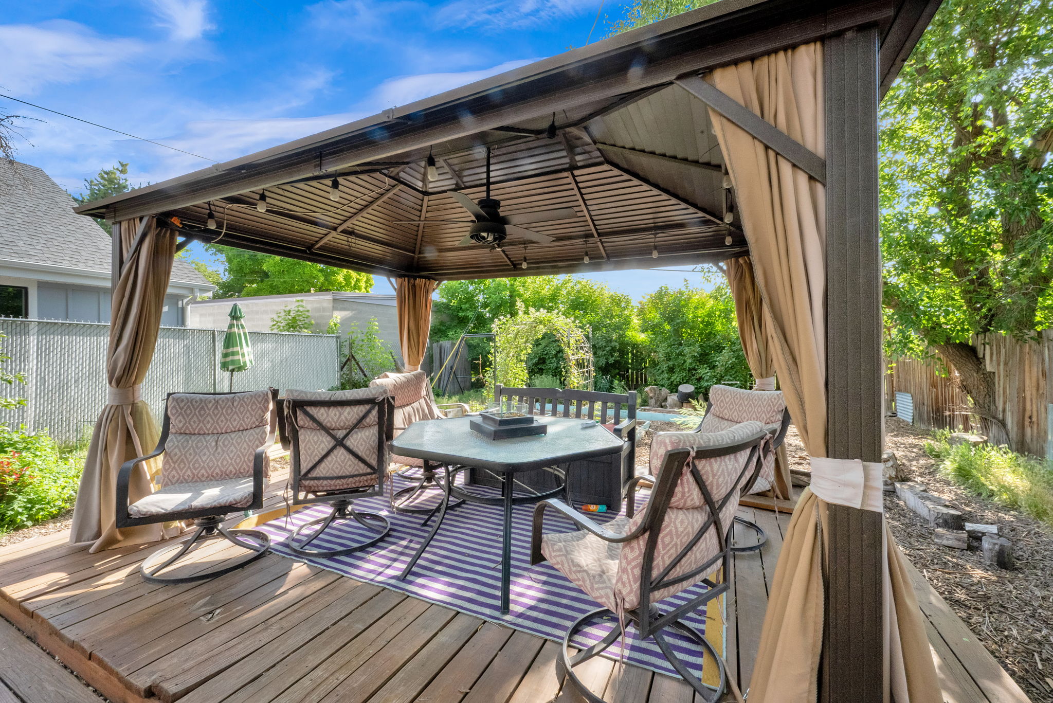 Expansive outdoor deck featuring a metal gazebo with integrated lighting and ceiling fan