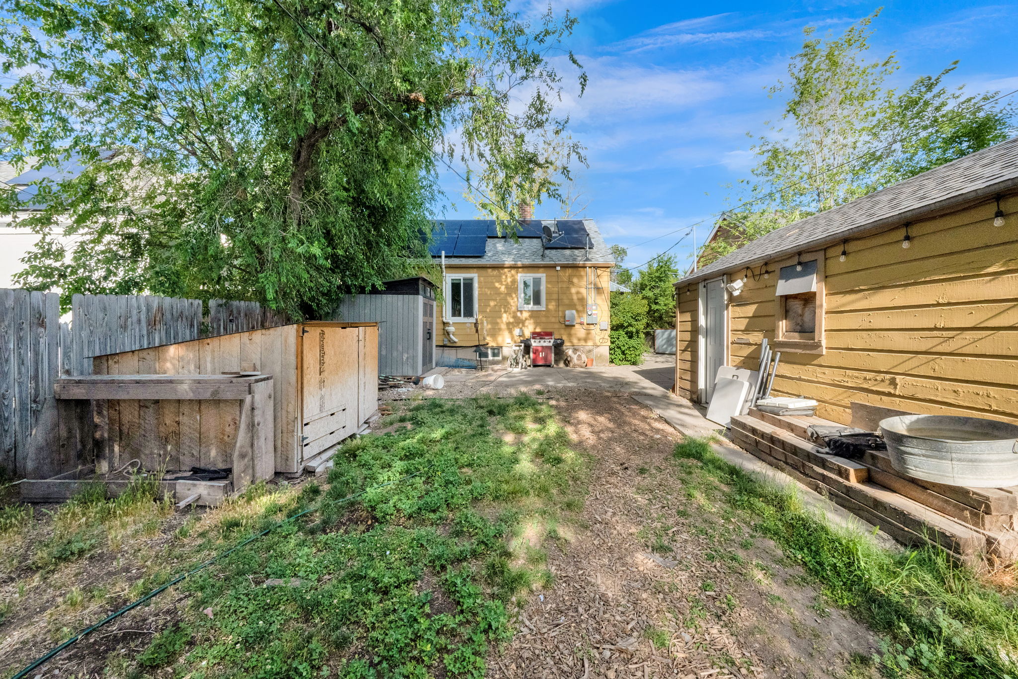 Fenced backyard featuring a gravel path and two accessory structures