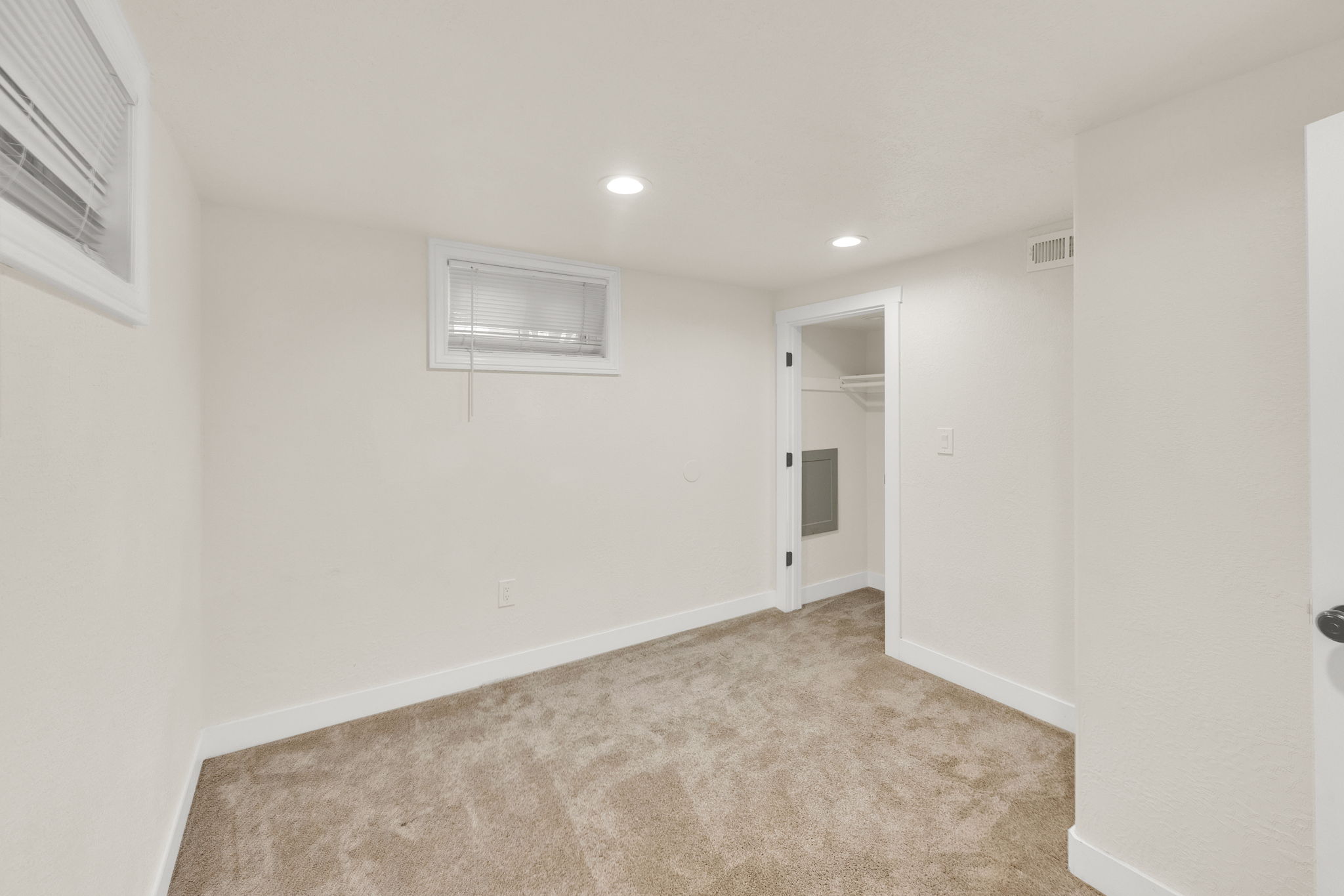 Carpeted room with recessed lighting and two windows featuring blinds