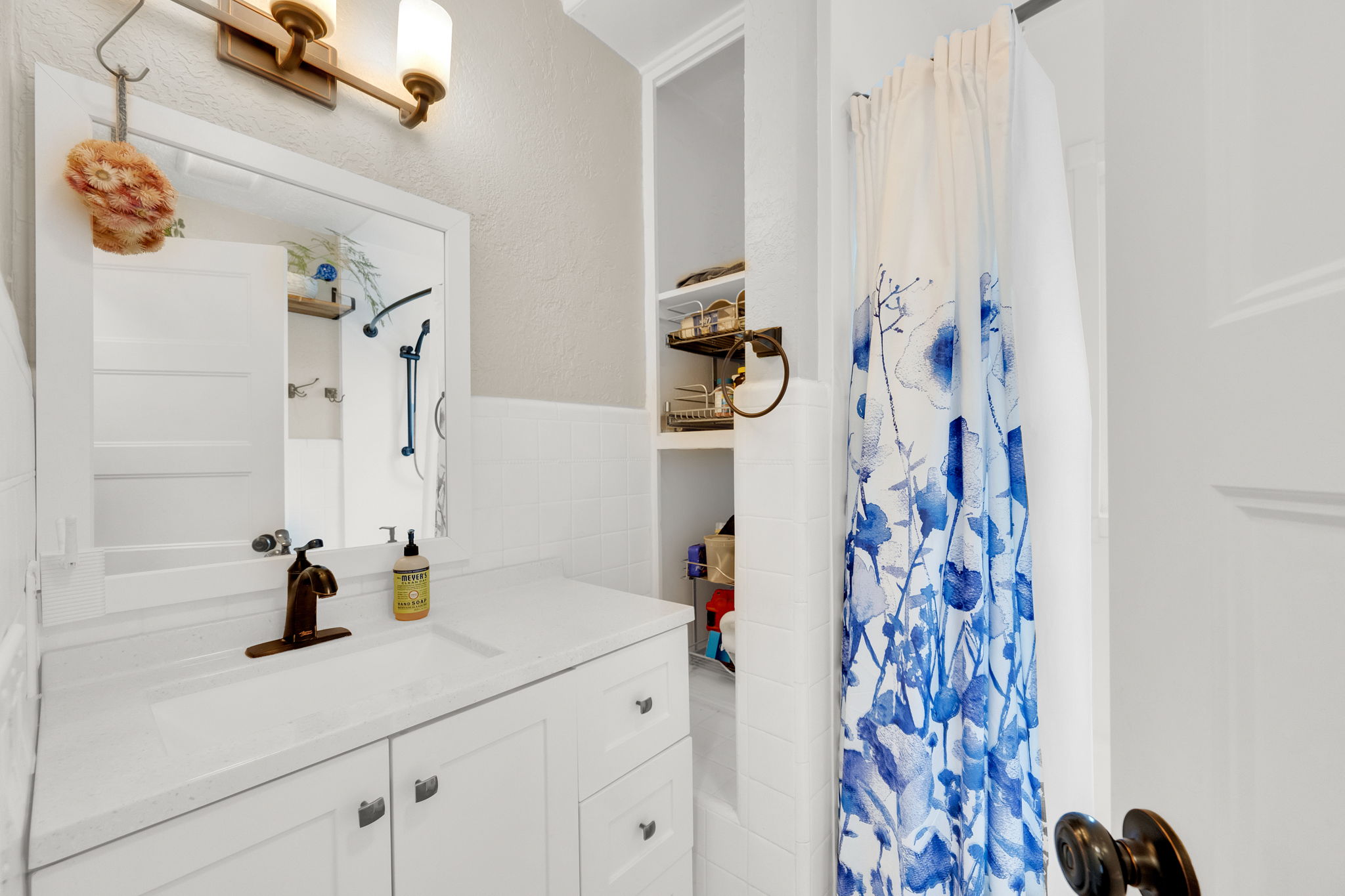 Bathroom featuring a white vanity with integrated sink, bronze-finish faucet, and a large framed mirror