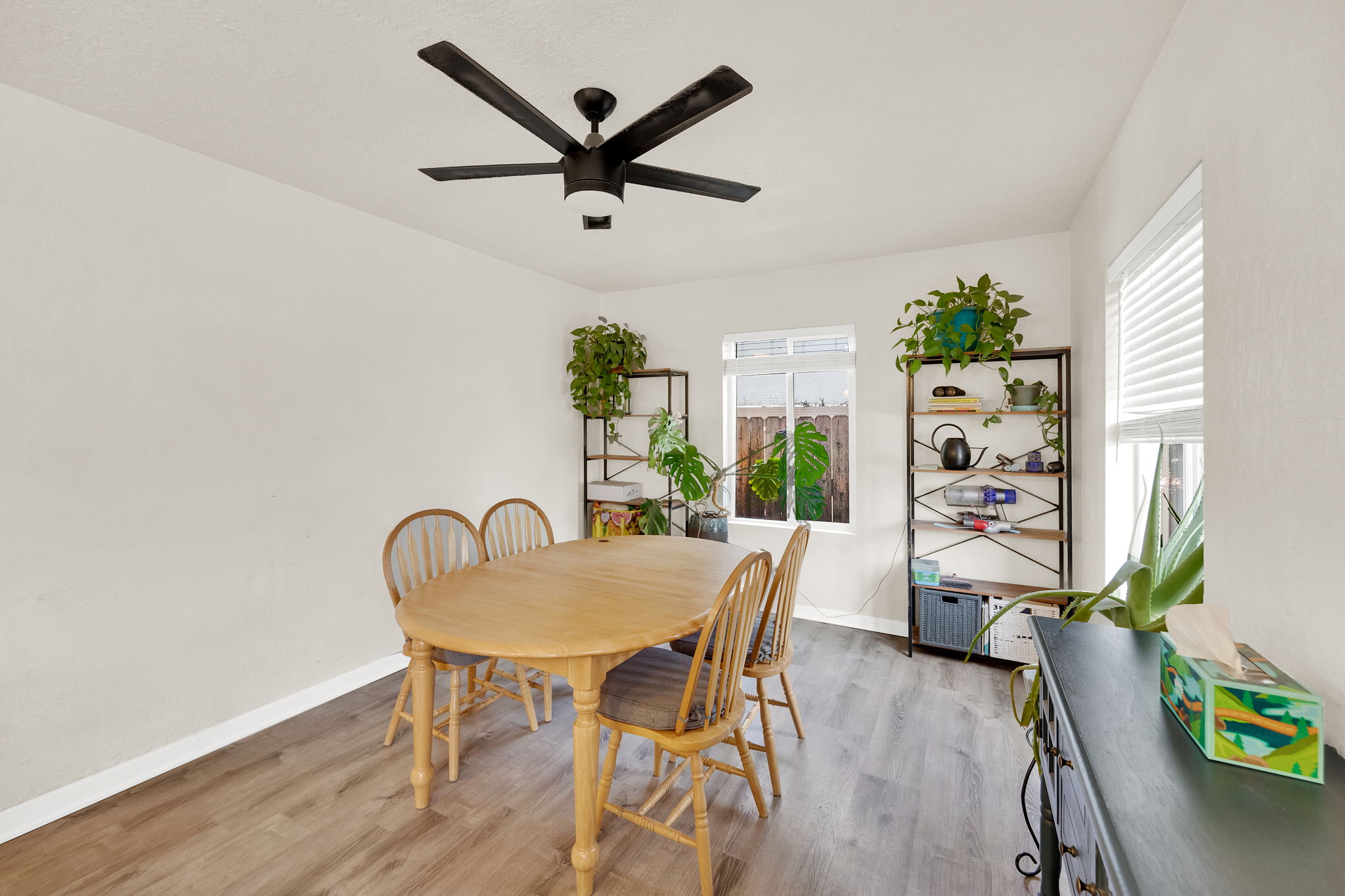 Dining area featuring wood-finish flooring, a modern black ceiling fan, and white walls