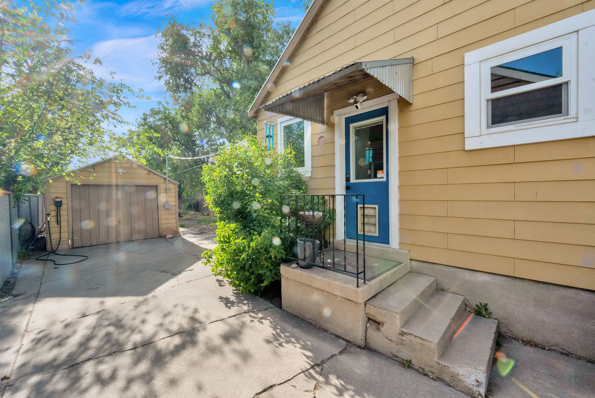 Exterior featuring light yellow siding and a vibrant blue entry door with an awning