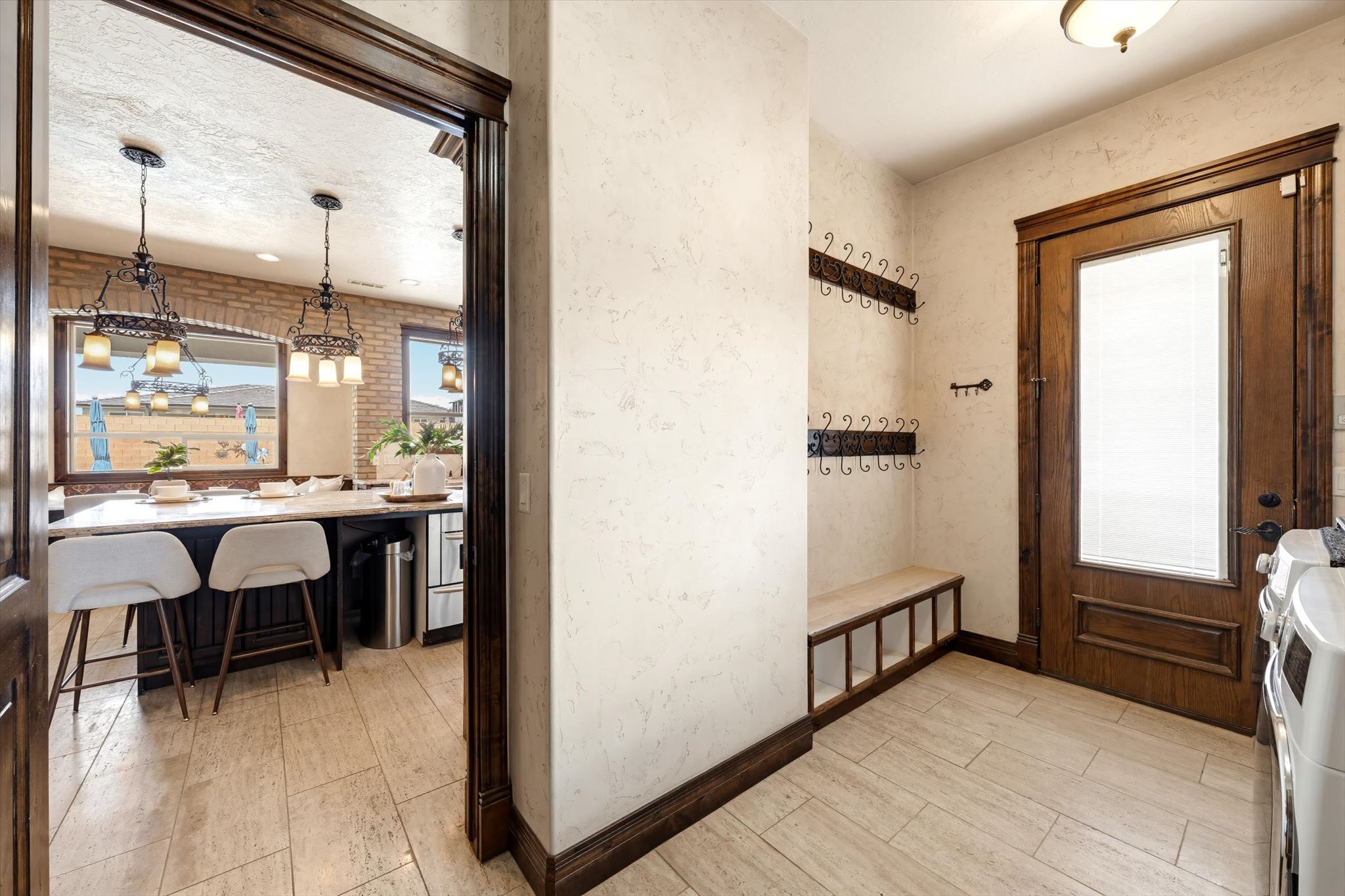 Entryway featuring wood-finish flooring, a built-in bench with storage, multiple wall-mounted coat racks, and a substantial wood-paneled door