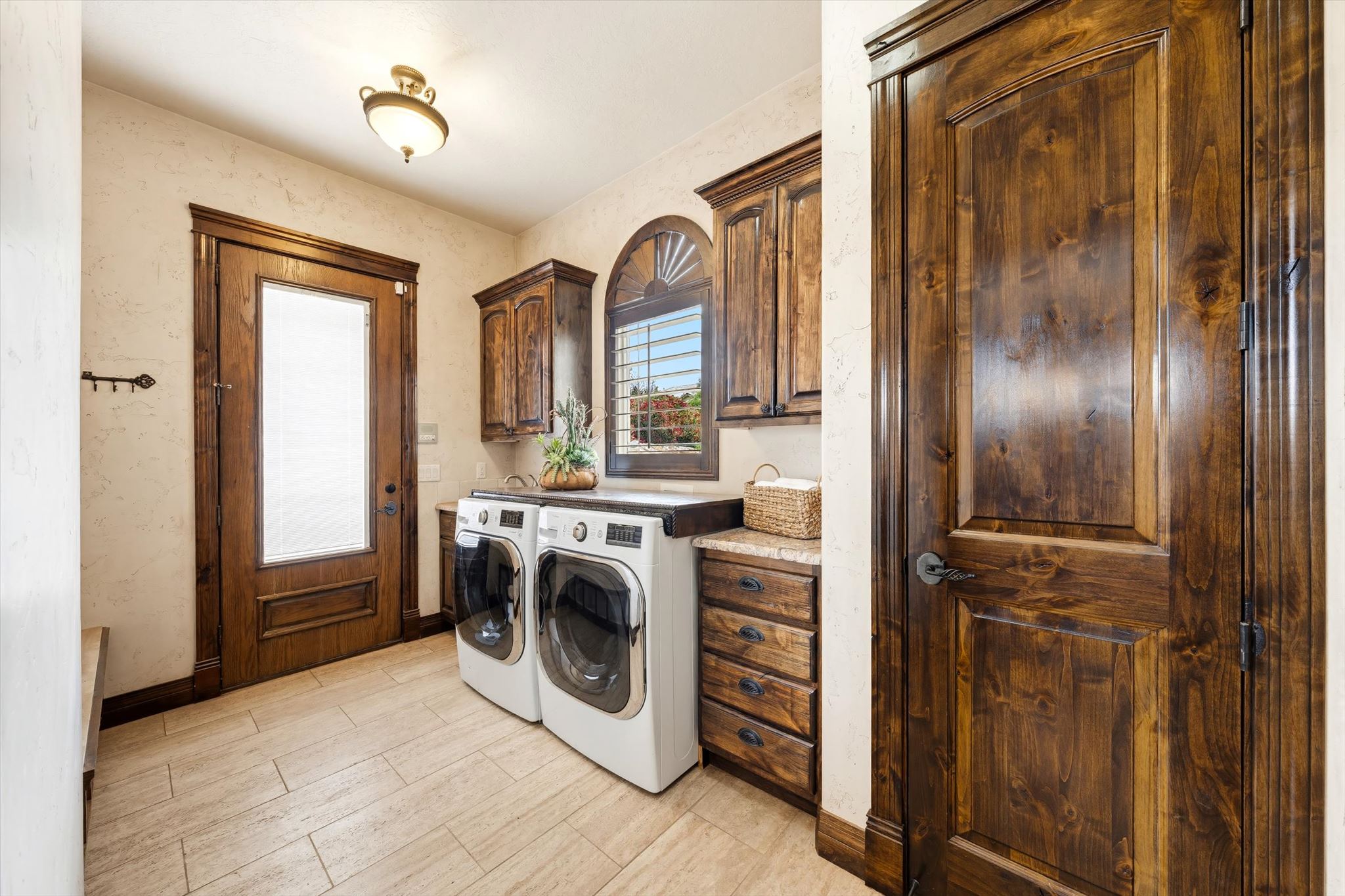Dedicated laundry room featuring wood-finish cabinetry, a solid surface countertop, and large format floor tiling