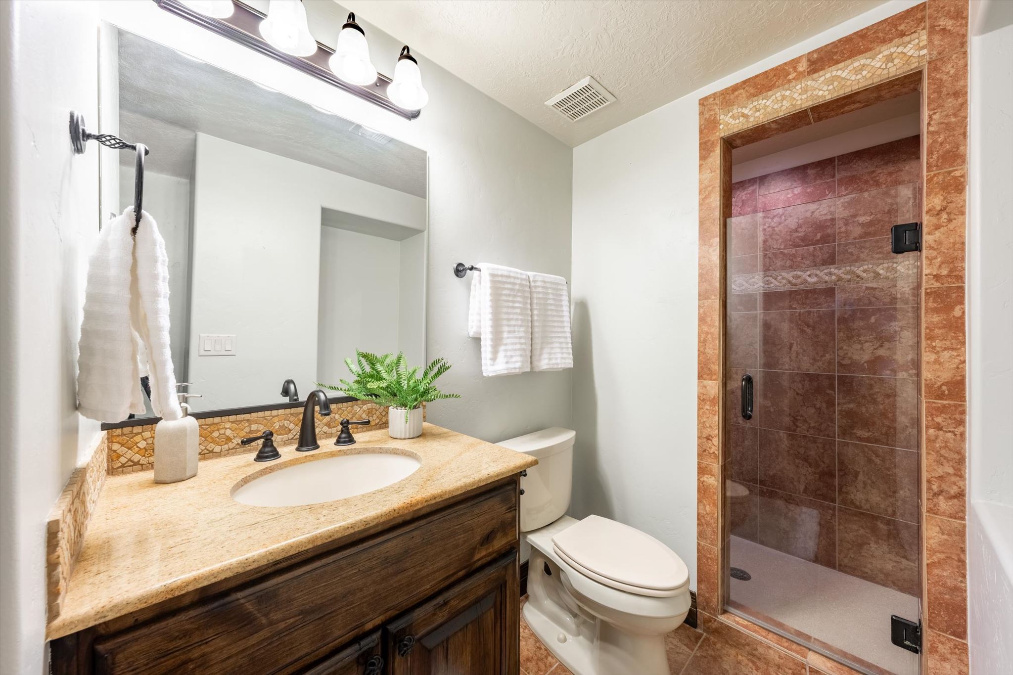 Bathroom featuring a dark wood vanity with a granite countertop, undermount sink, and dark bronze fixtures