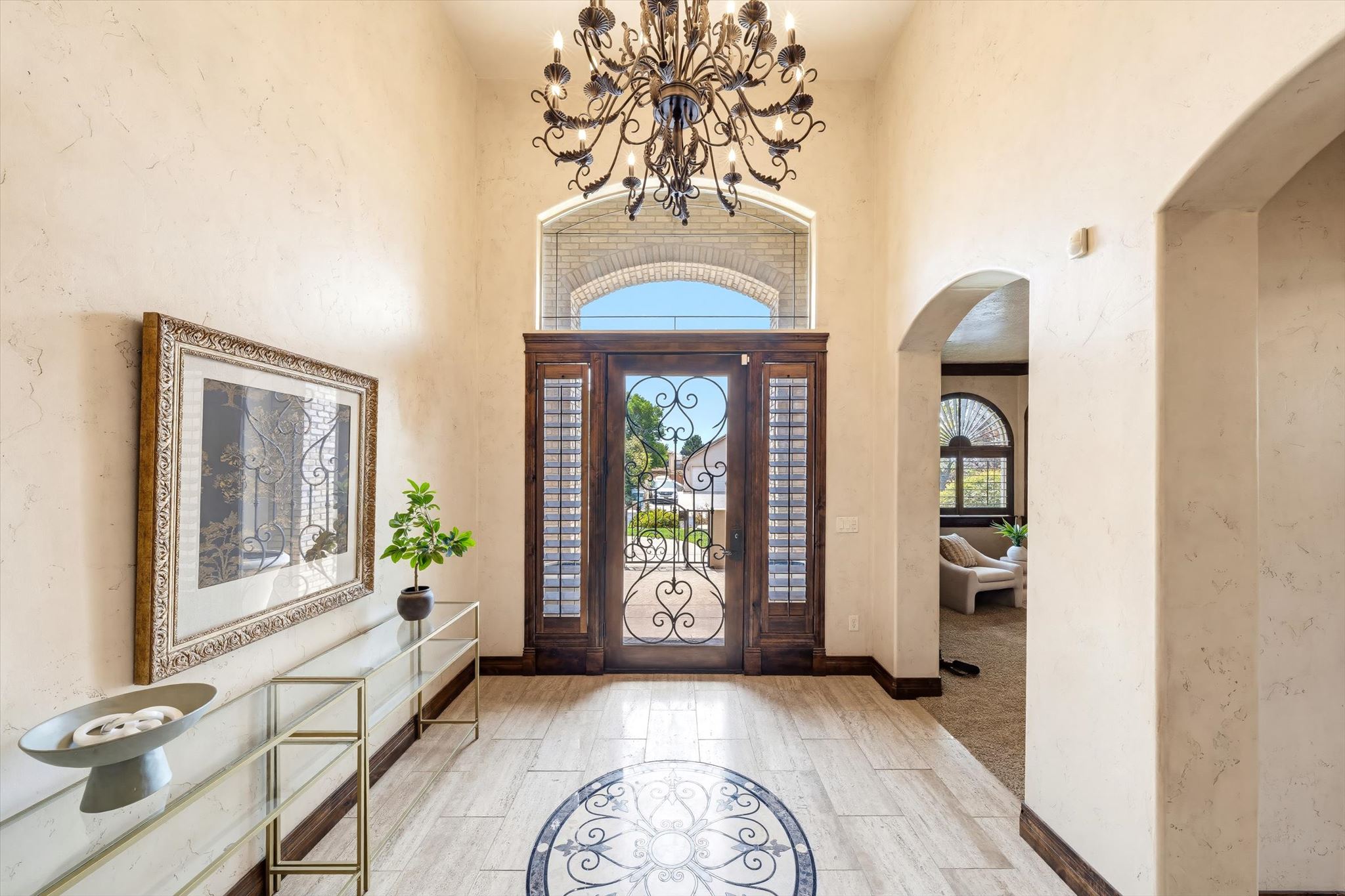 Grand entryway featuring a decorative dark wood front door with wrought iron detailing and an arched transom window
