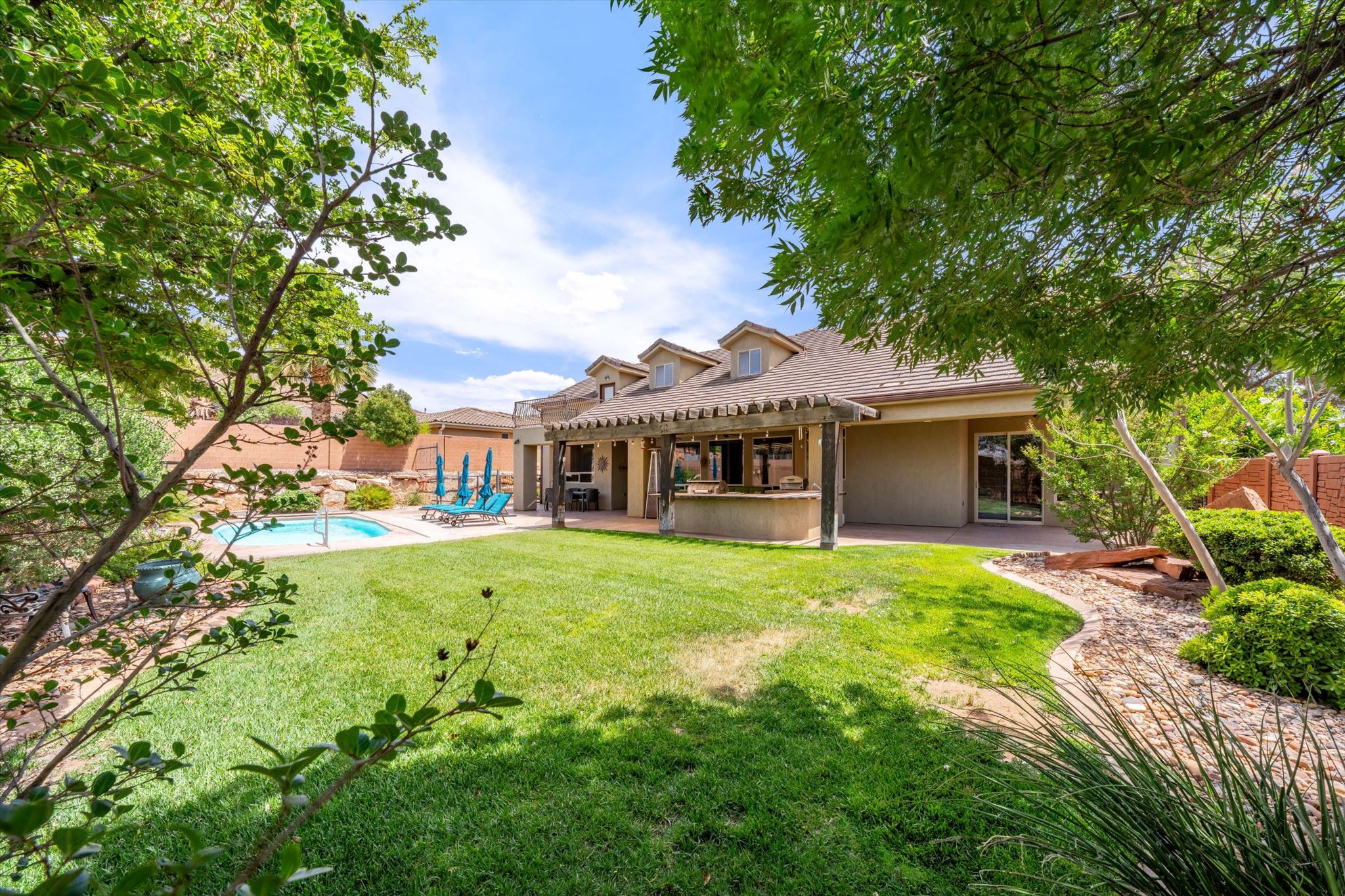 Expansive backyard featuring a large lawn, a built-in swimming pool, and mature trees
