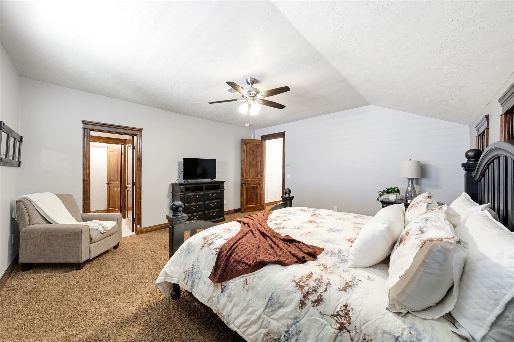 Spacious room featuring vaulted ceilings, a ceiling fan, and warm-toned carpet flooring