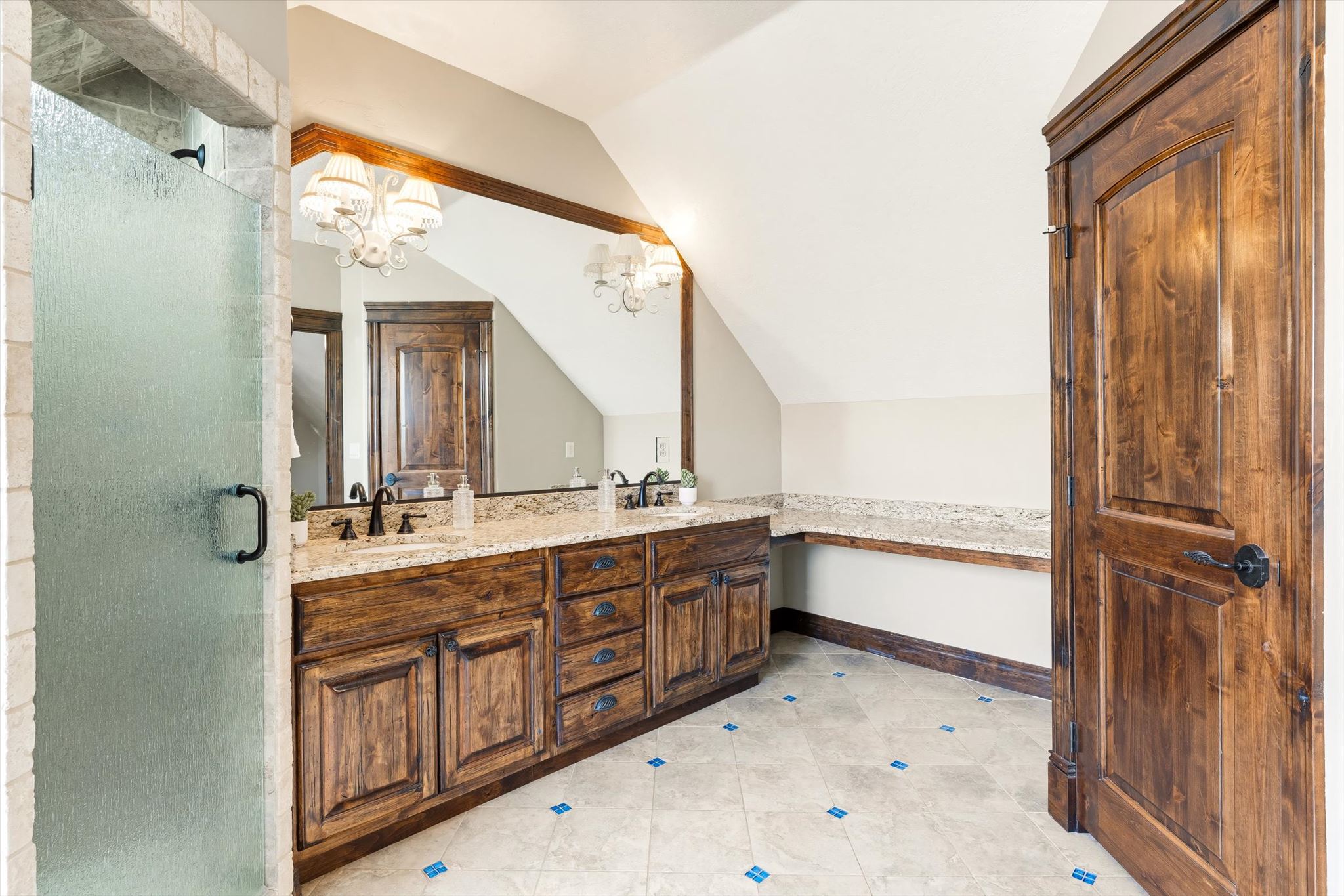 Spacious bathroom featuring a dual vanity with granite countertops, rich wood cabinetry, and integrated sinks