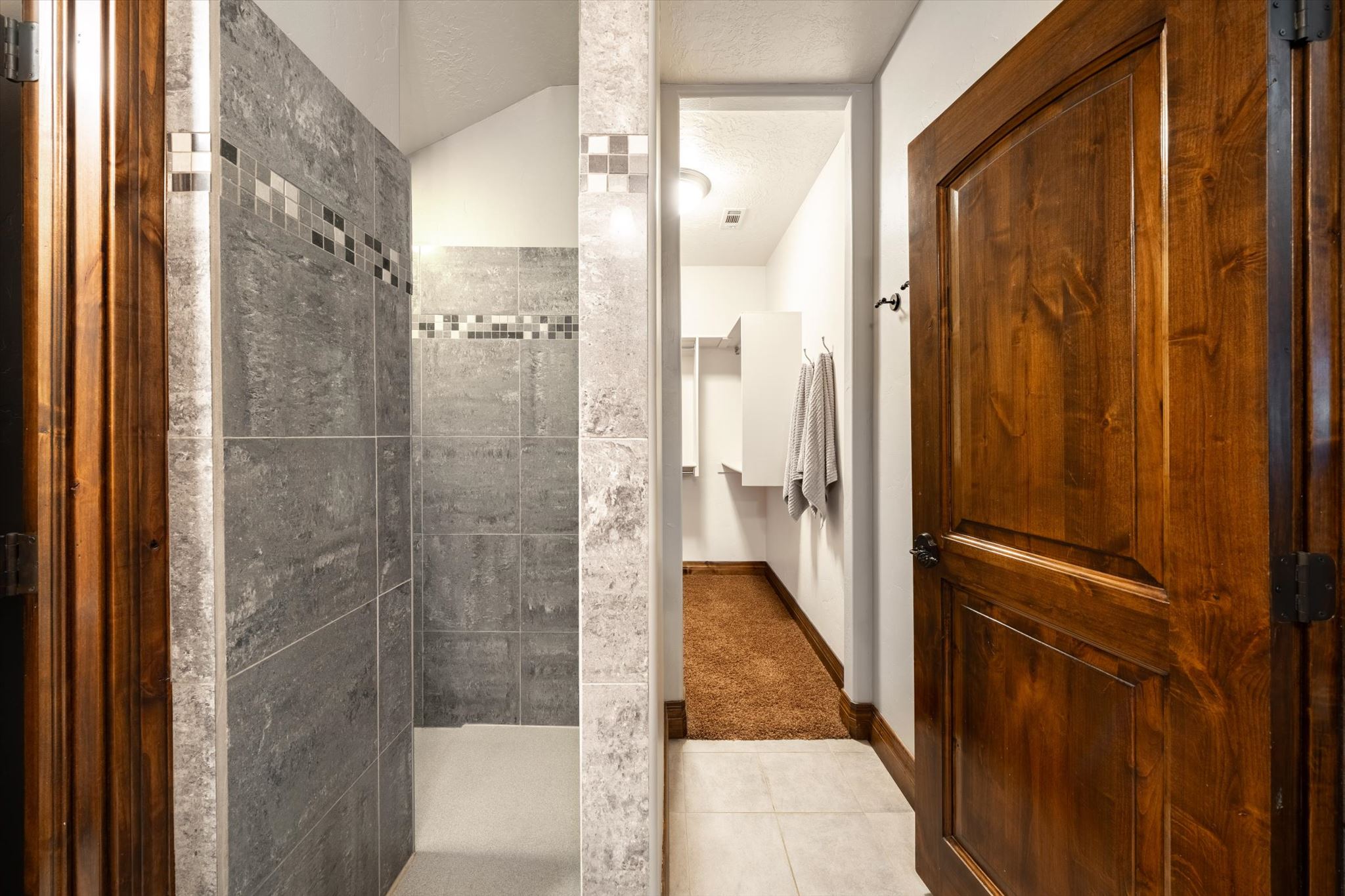 Tiled shower enclosure featuring a decorative mosaic border