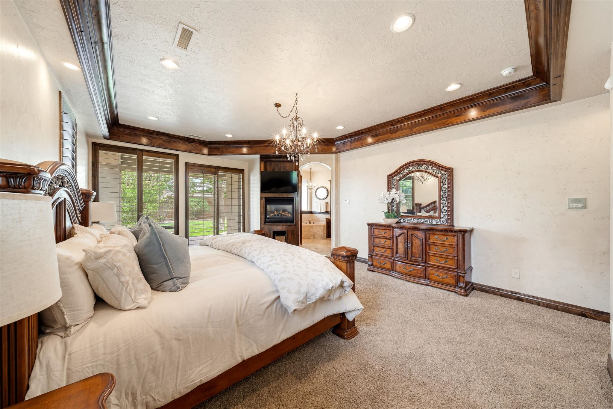 Spacious bedroom featuring warm-toned carpeting and decorative ceiling beams