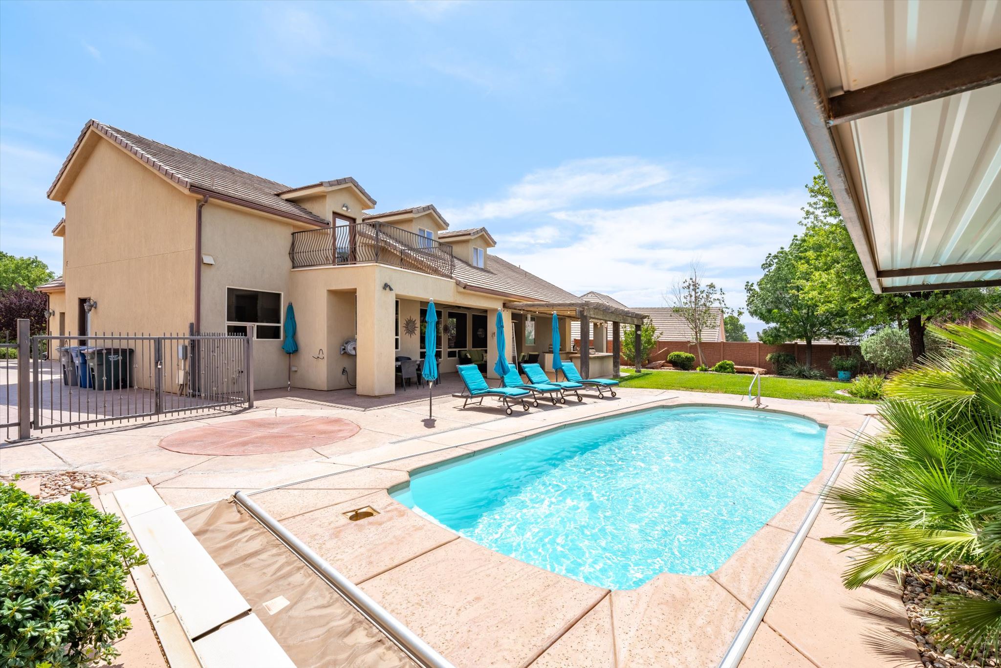 Rear exterior featuring a rectangular in-ground pool with concrete coping, surrounded by a spacious concrete patio