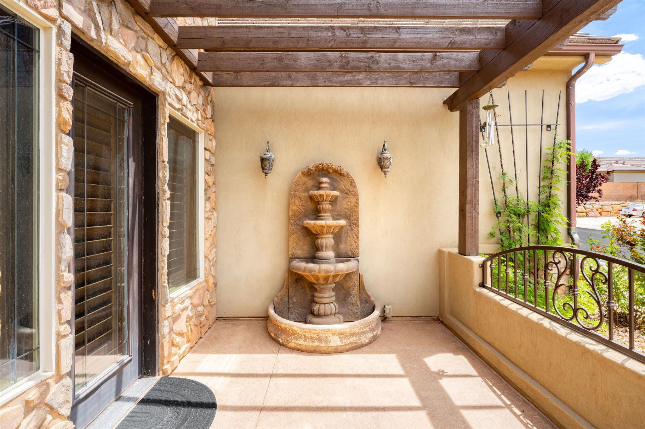 Covered patio featuring a three-tiered fountain, stucco walls, and a stone facade