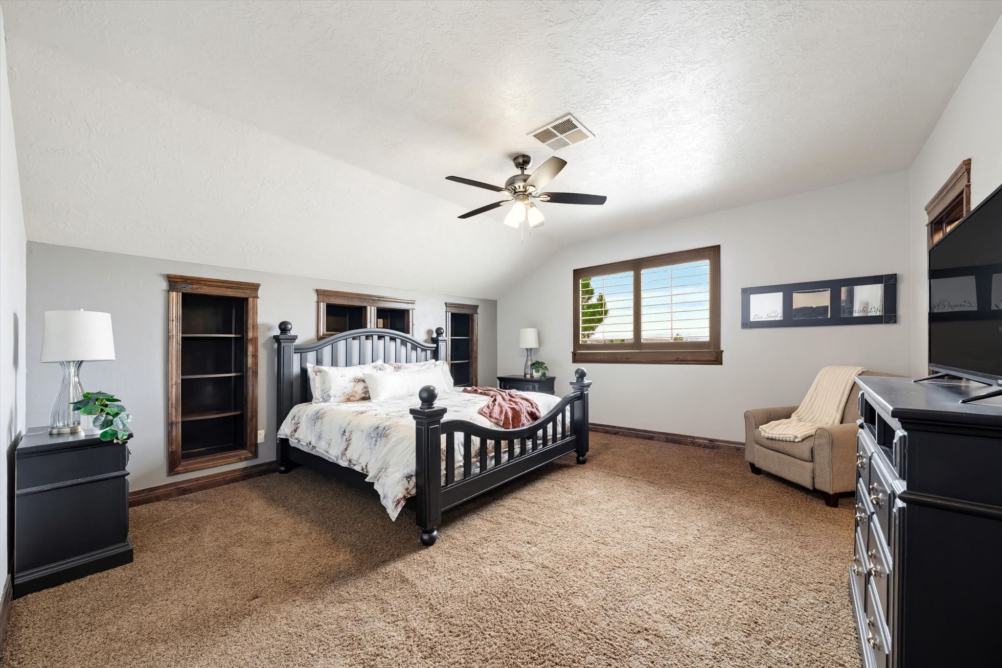 Spacious room featuring vaulted ceilings, a ceiling fan, and plush carpeting