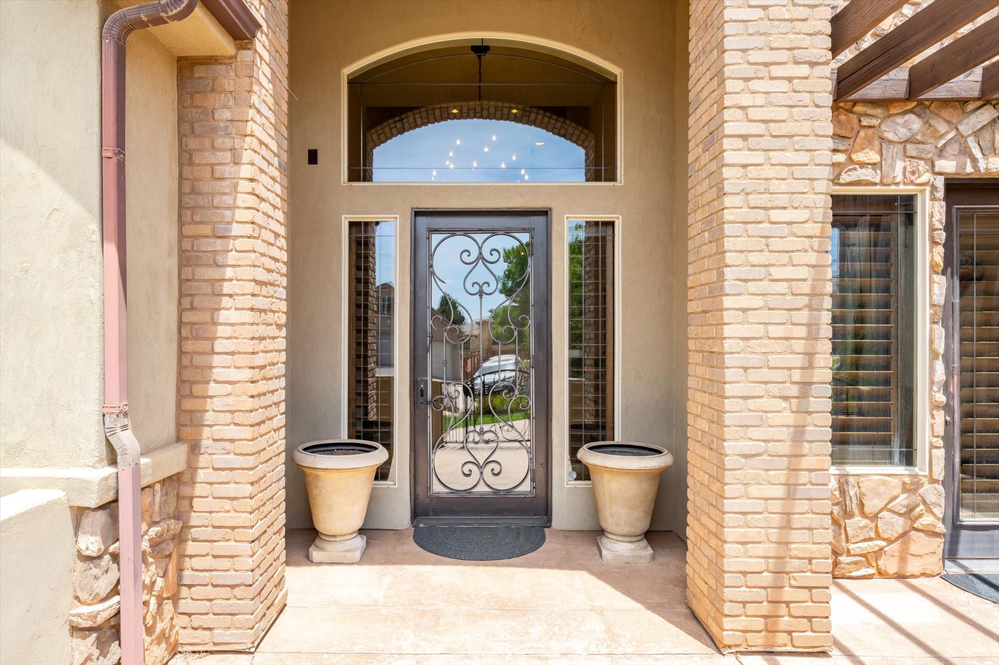 Arched entryway featuring a wrought iron and glass front door, two slender sidelight windows, and an arched transom window above
